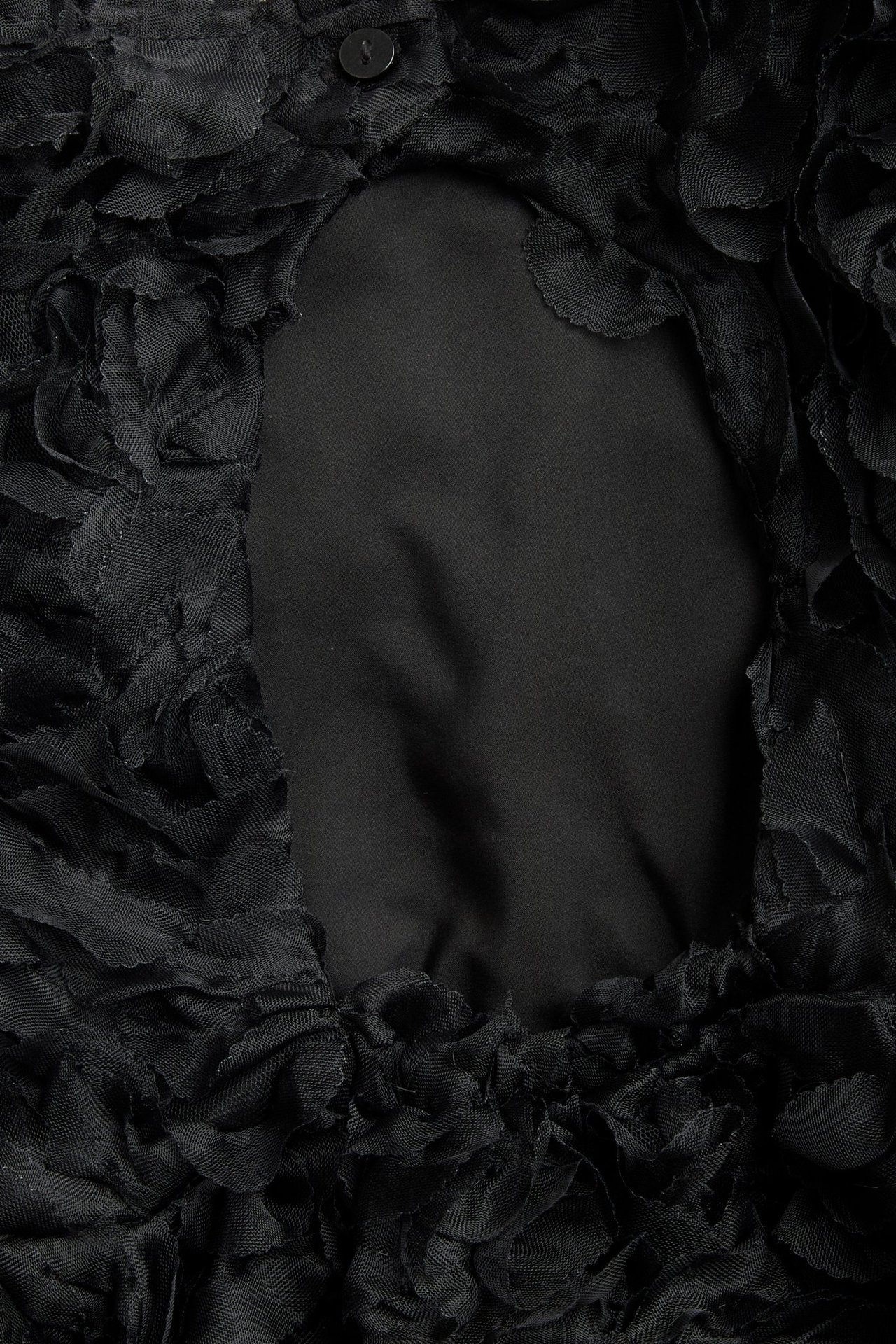 Zbliżenie widoku z tyłu czarnej sukienki dziecięcej z siateczką 3D i guzikiem u góry.