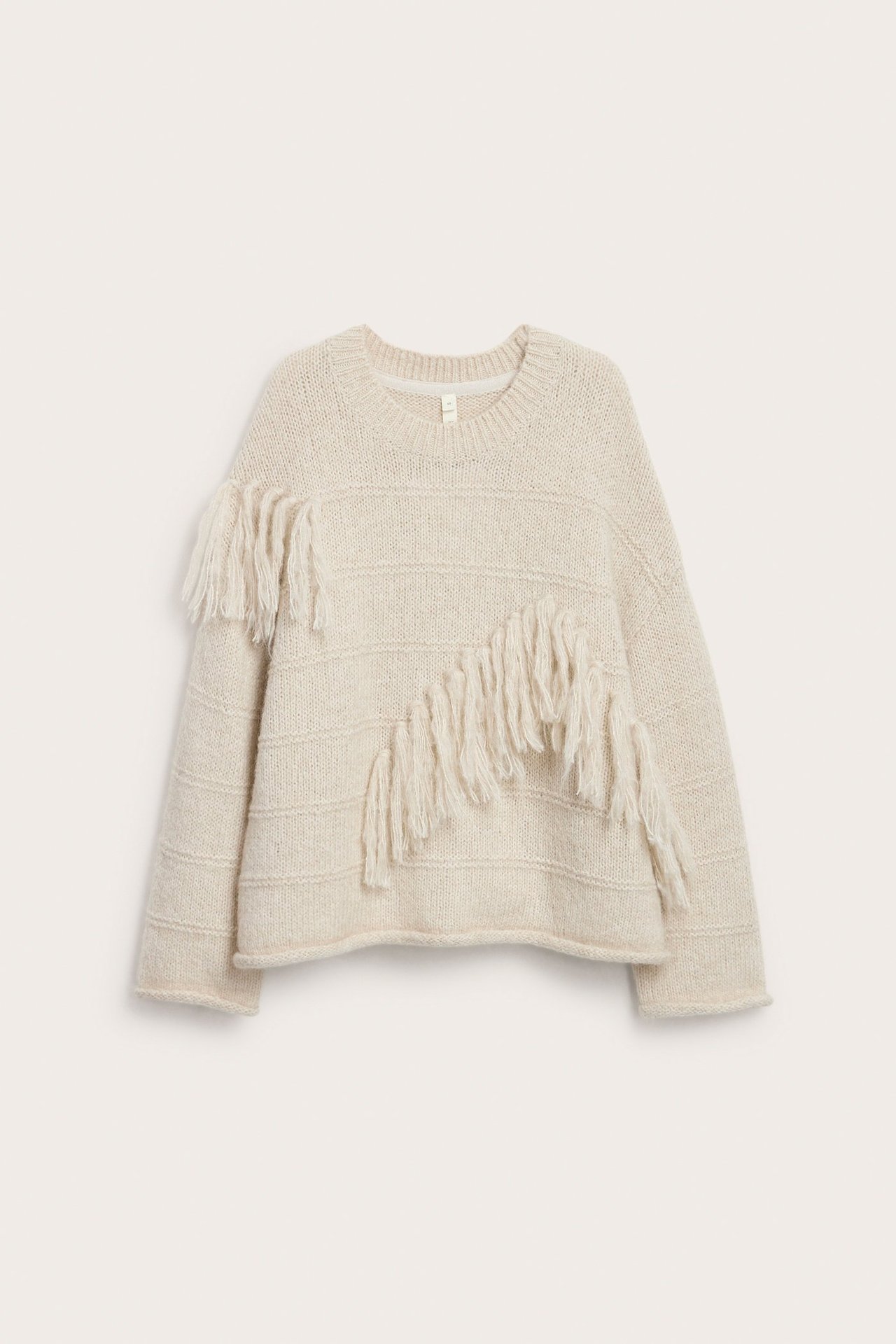 Frontvisning: Lys beige grovstrikket ullgenser med dekorative frynser.
