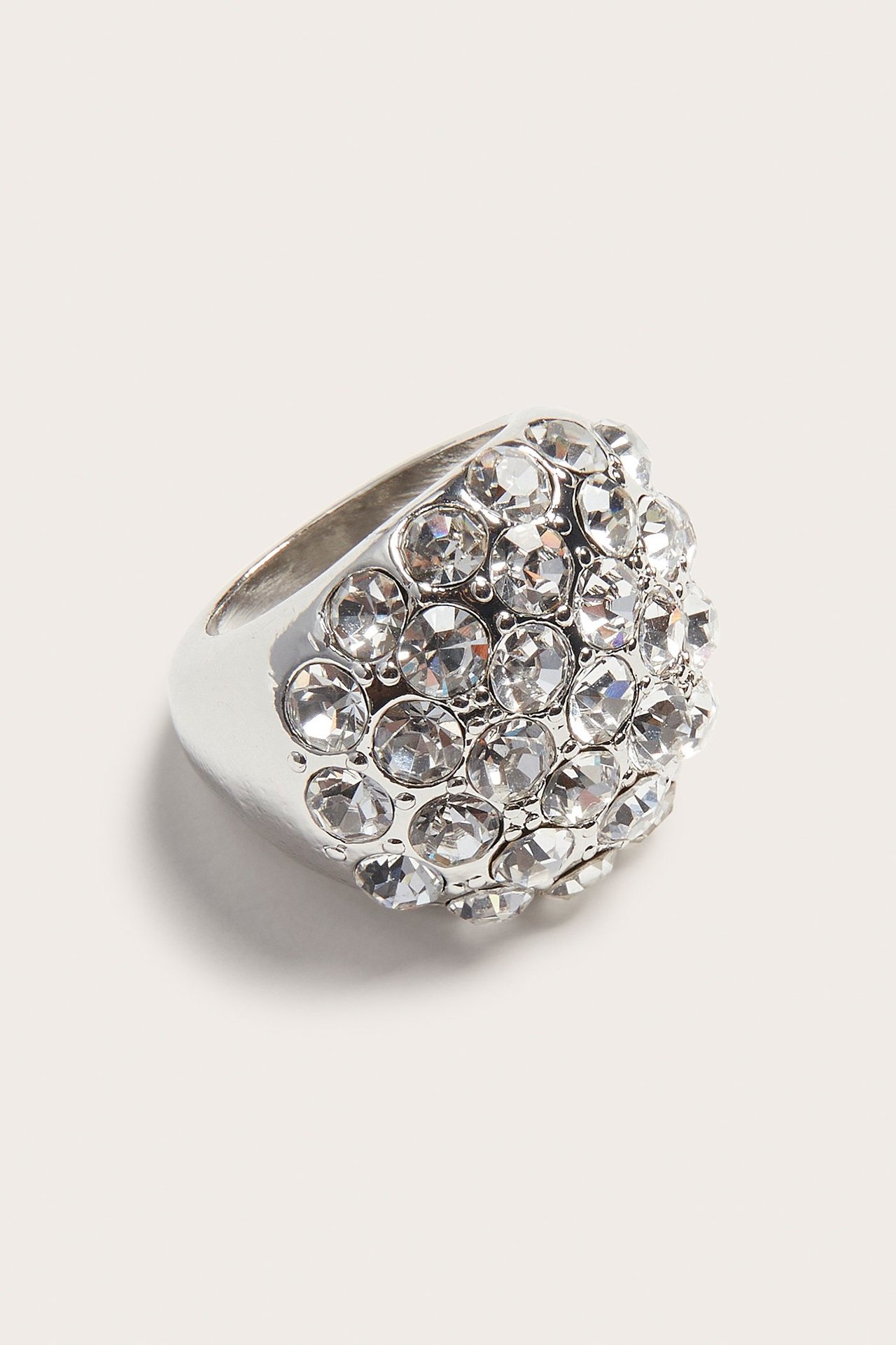 Ring i vit metall med många strass-stenar, enfärgad, nära vy.