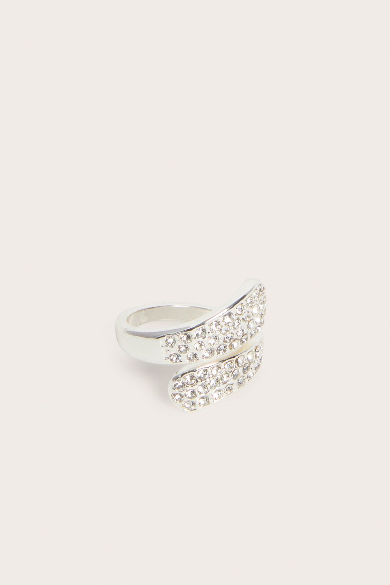 Närbild av en silverfärgad vriden ring, prydd med klara strass på dess omlottdesign.