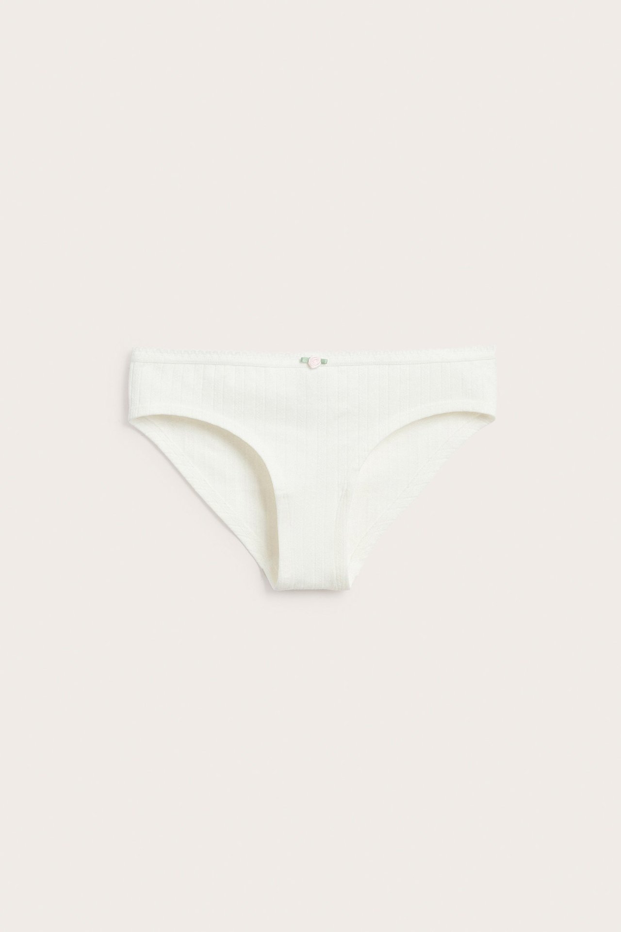 Edestä luonnonvalkoiset pointelle-ribbit alushousut, pieni vaaleanpunainen ruusu vyötäröllä.