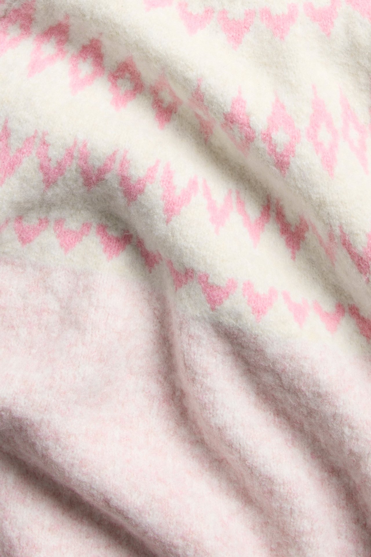 Mjuk rosa stickad kortärmad tröja med fairisle jaquard på modellens överkropp.