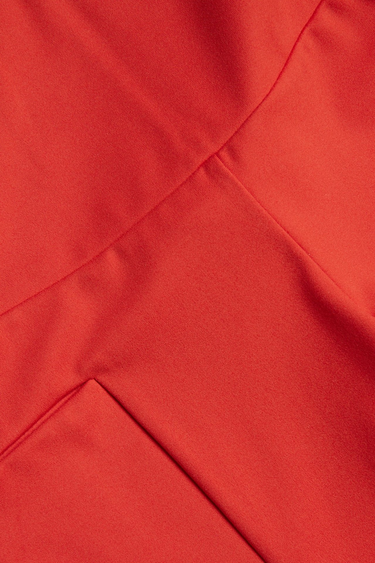 Zbliżenie czerwonego materiału dżersejowego kolarek, z matowym wykończeniem i widocznymi szwami.