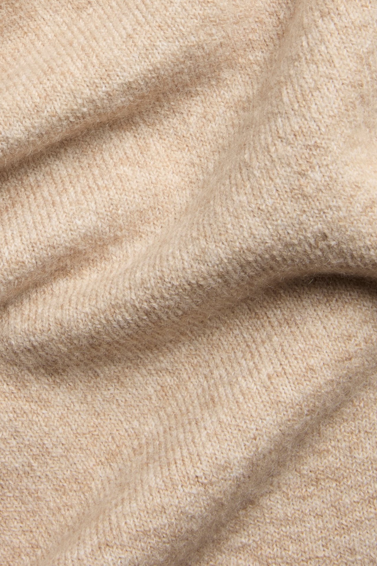 Zbliżenie beżowego melanżowego materiału dzianinowego, prawdopodobnie z dzianinowego t-shirtu.