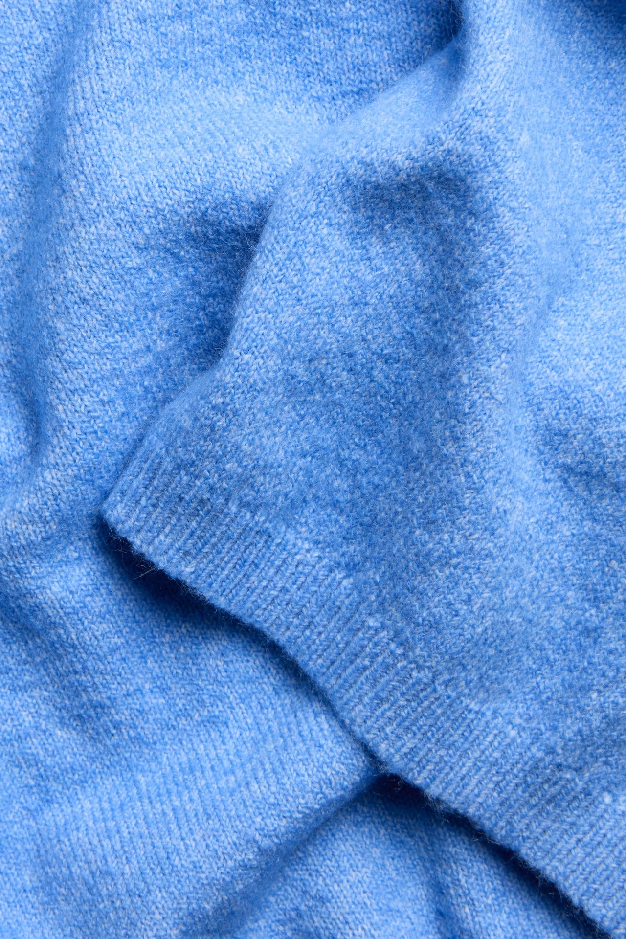 Zbliżenie na niebieski melanżowy dzianinowy T-shirt z prążkowanym ściągaczem.