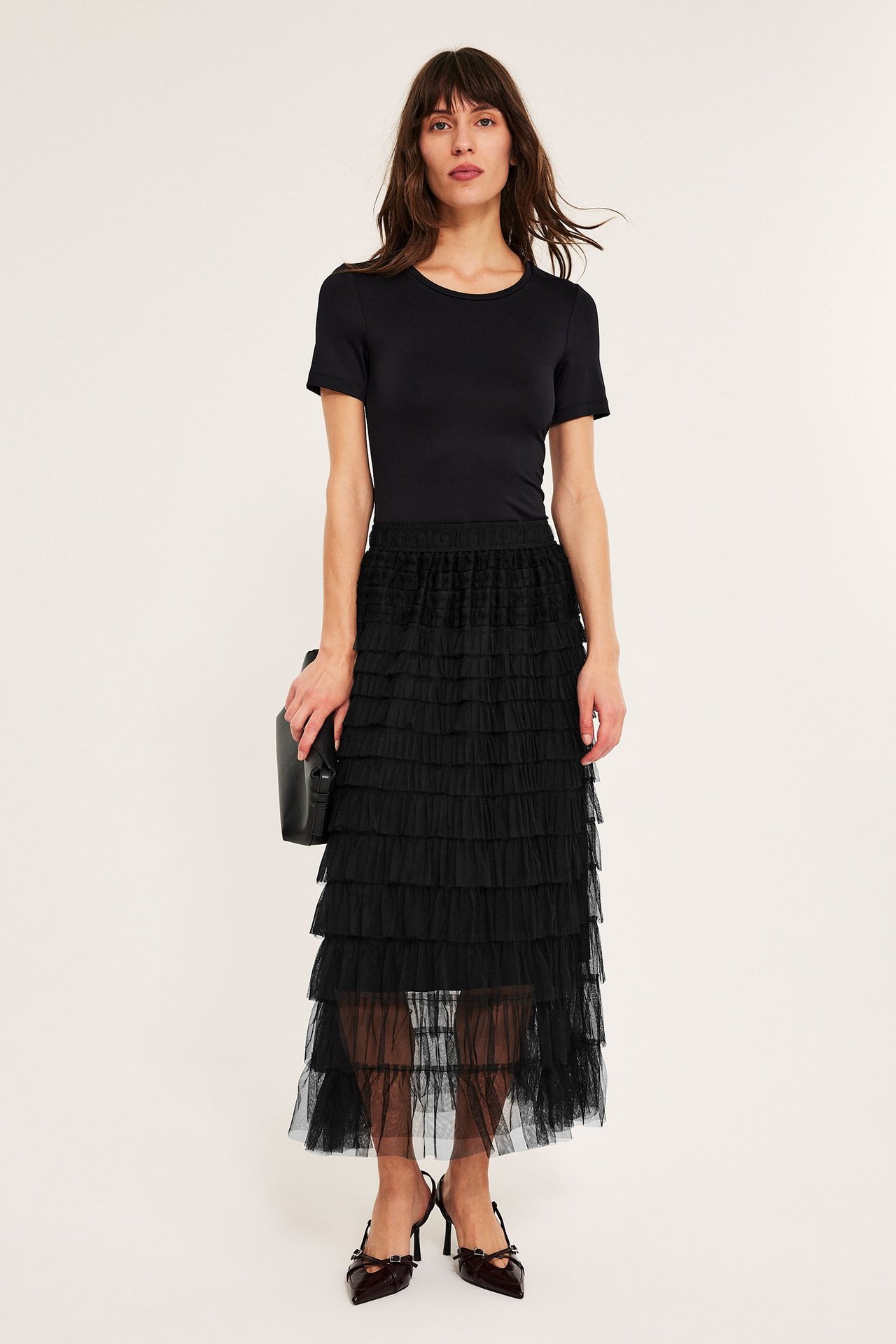 Długa czarna spódnica z tiulu z frędzlami, elastyczny pas, na kobiecie.