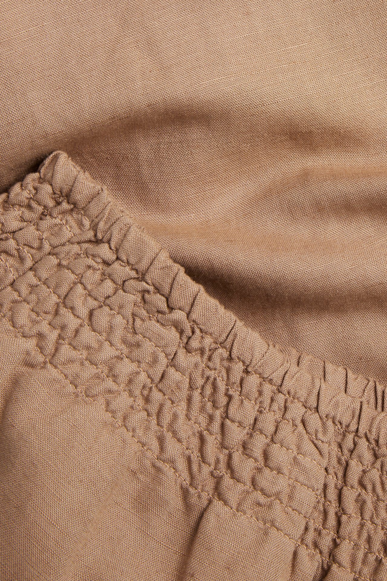 Närbild på beiga byxor i linnemix med smockresår i midjan.