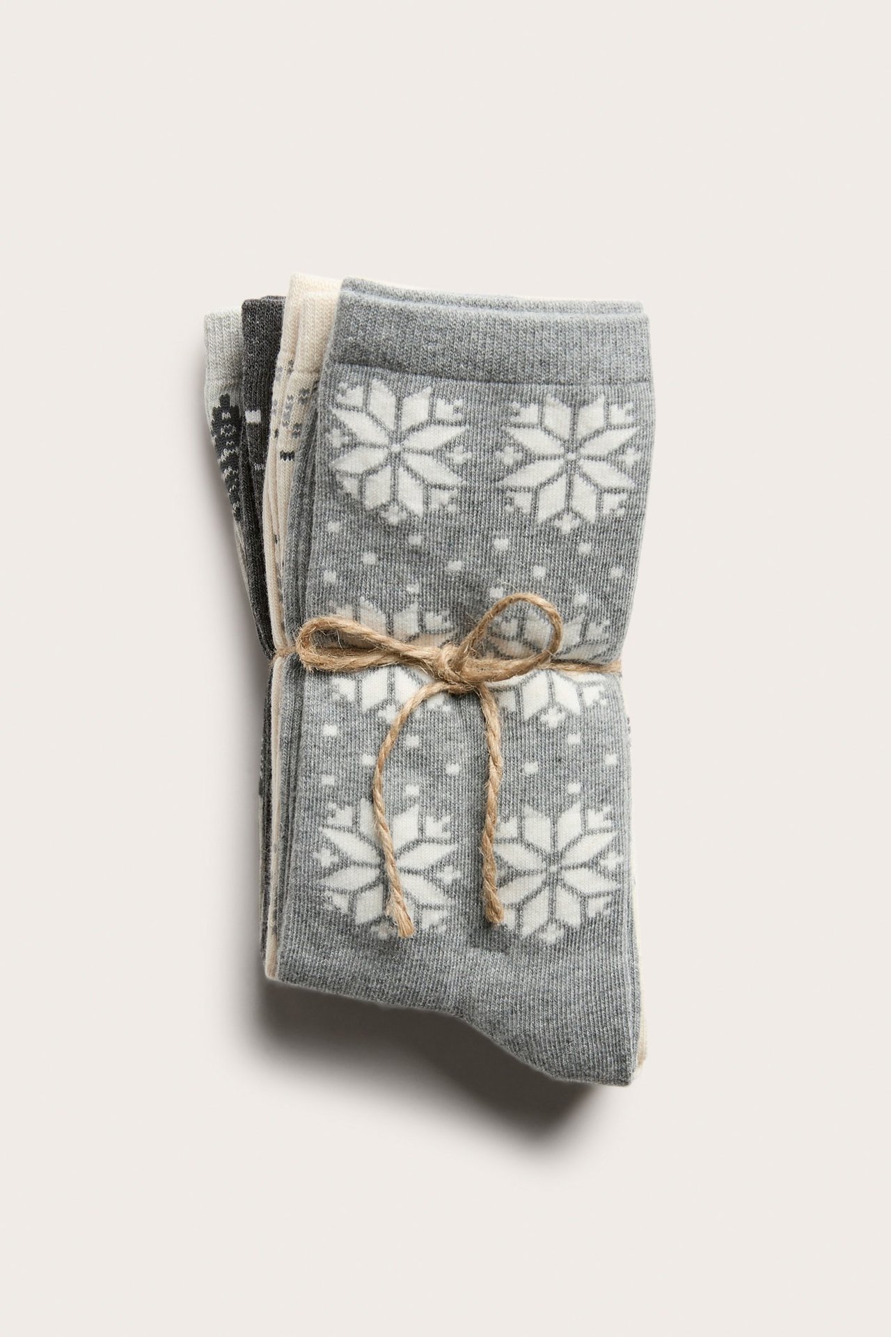 Złożone szare skarpety w białe płatki śniegu, pakiet czterech sztuk, przewiązane sznurkiem.