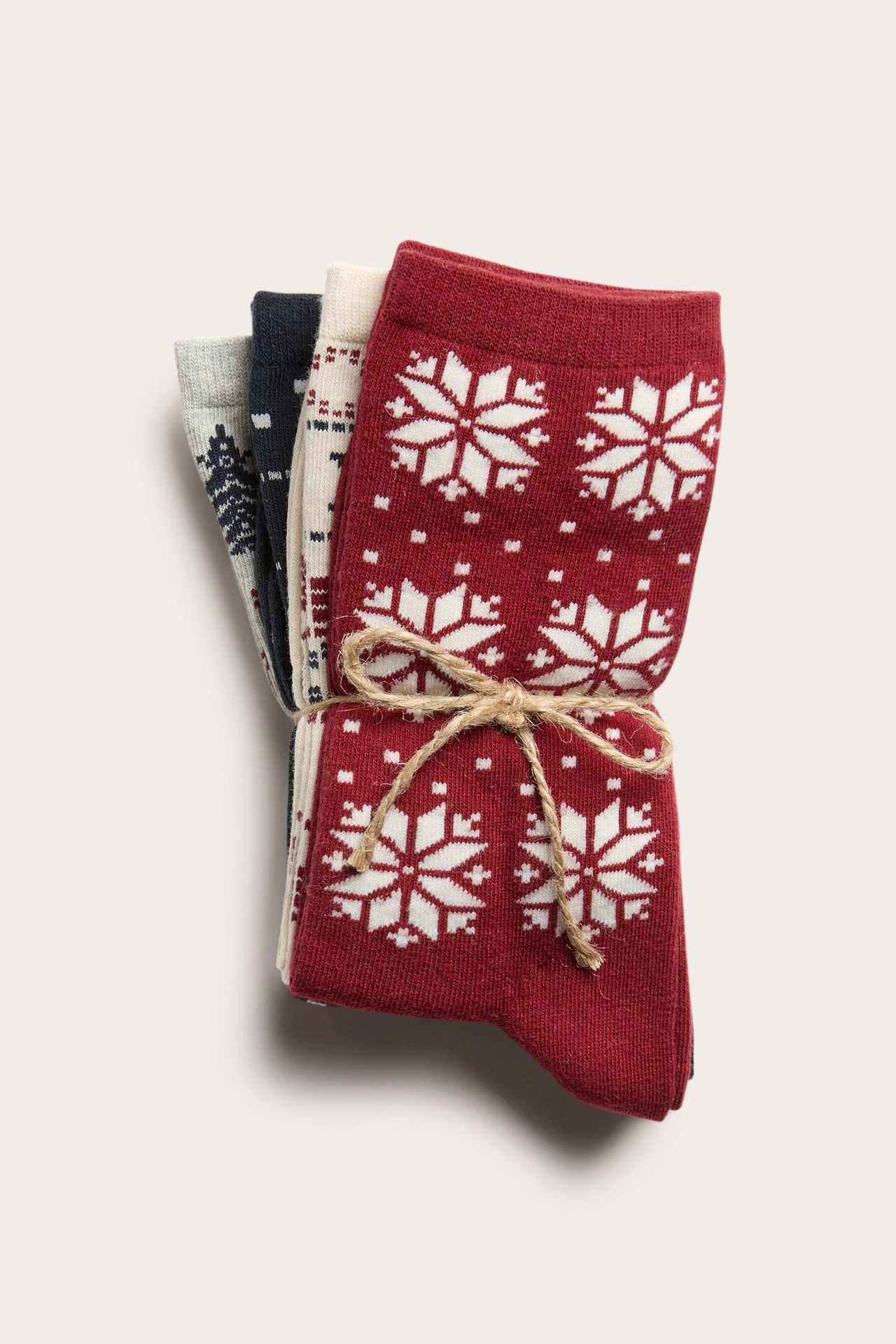 Widok z góry: Cztery bawełniane skarpety ze sznurkiem. Górna jest czerwona w białe płatki śniegu.