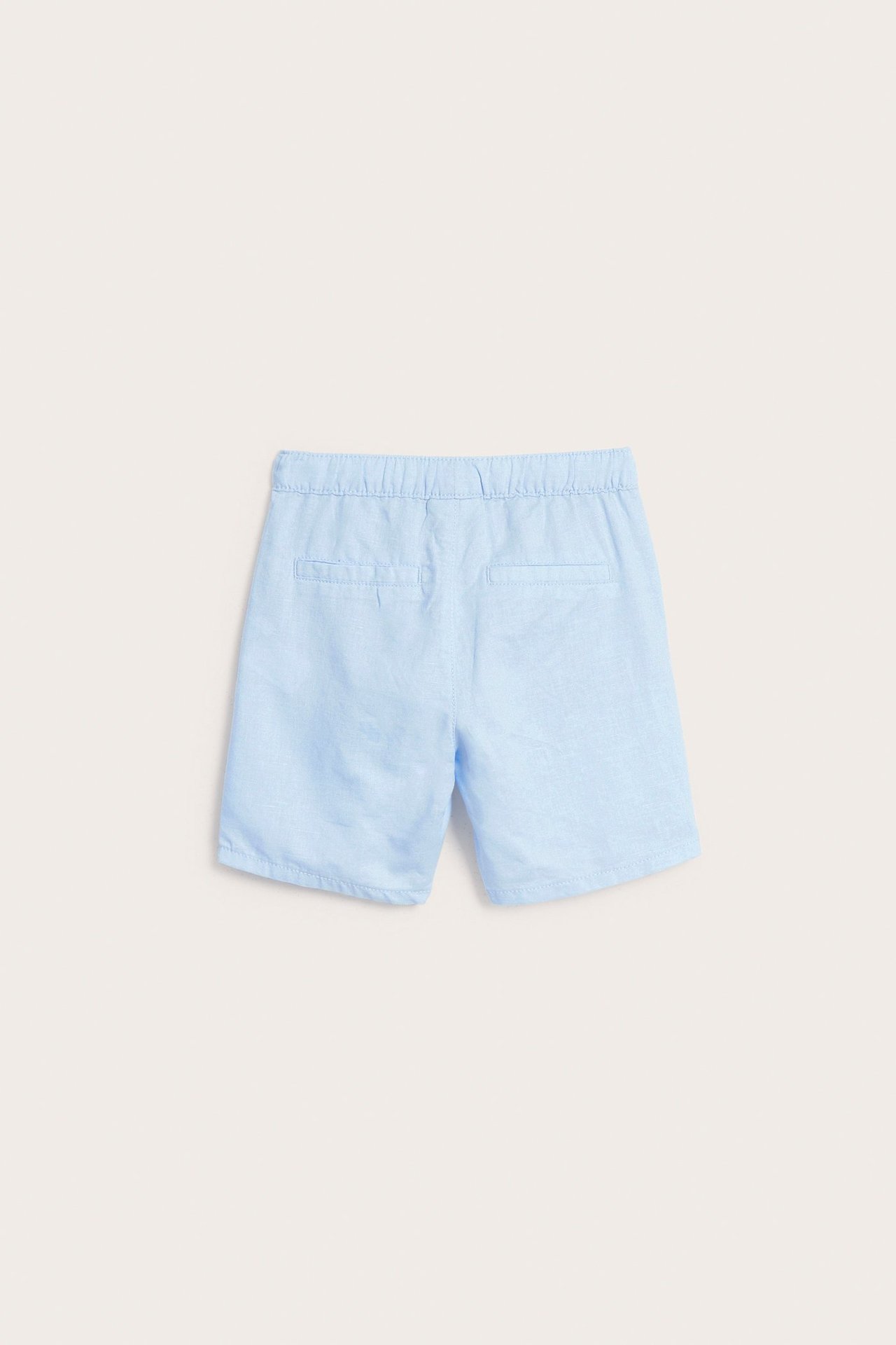 Widok z tyłu: Jasnoniebieskie szorty lniane dla dzieci z elastyczną talią i dwoma atrapami kieszeni z tyłu.