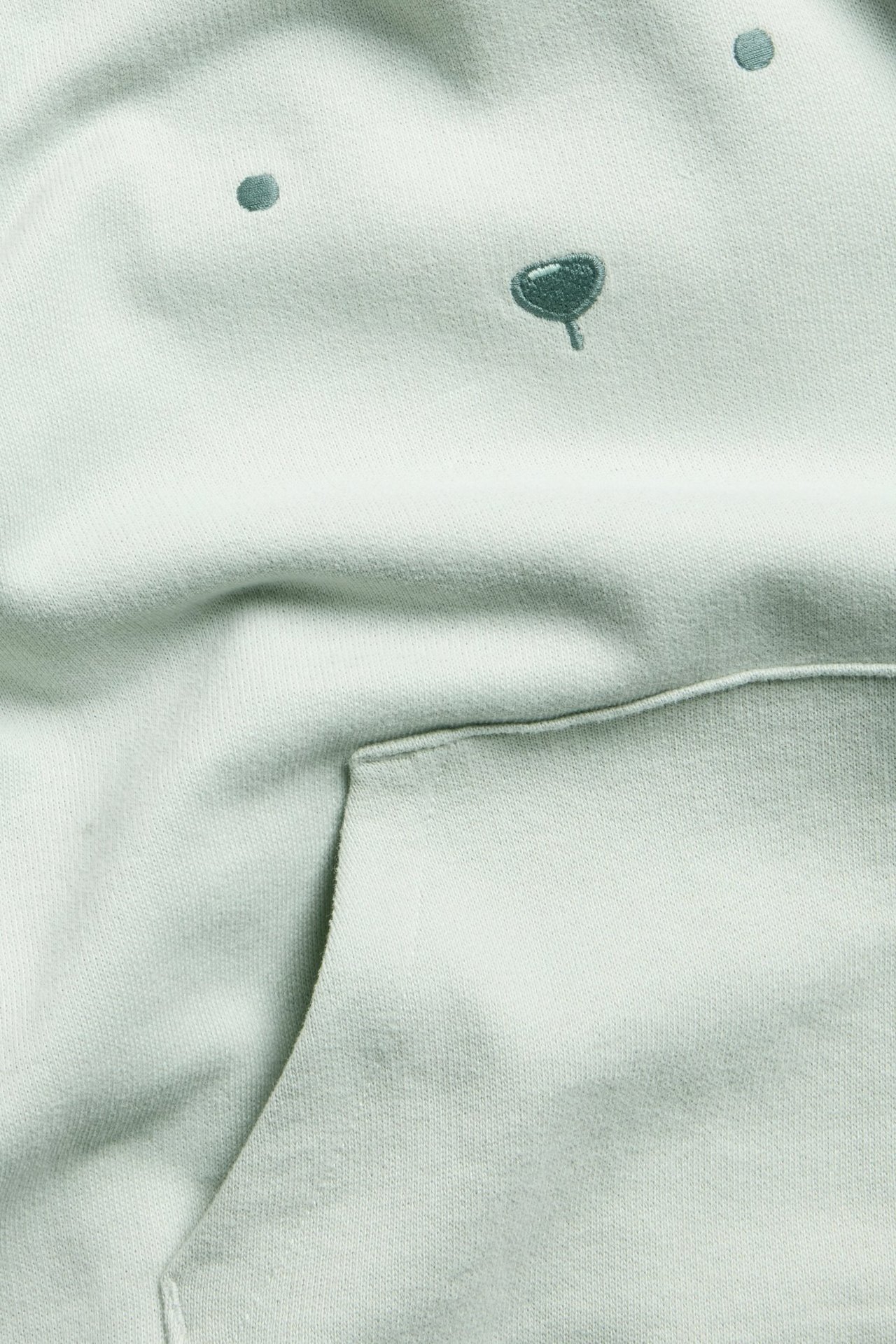 Miękka zielona bluza z nadrukiem medy, riby u dekoltu, rękawów i u dołu, widok z przodu.