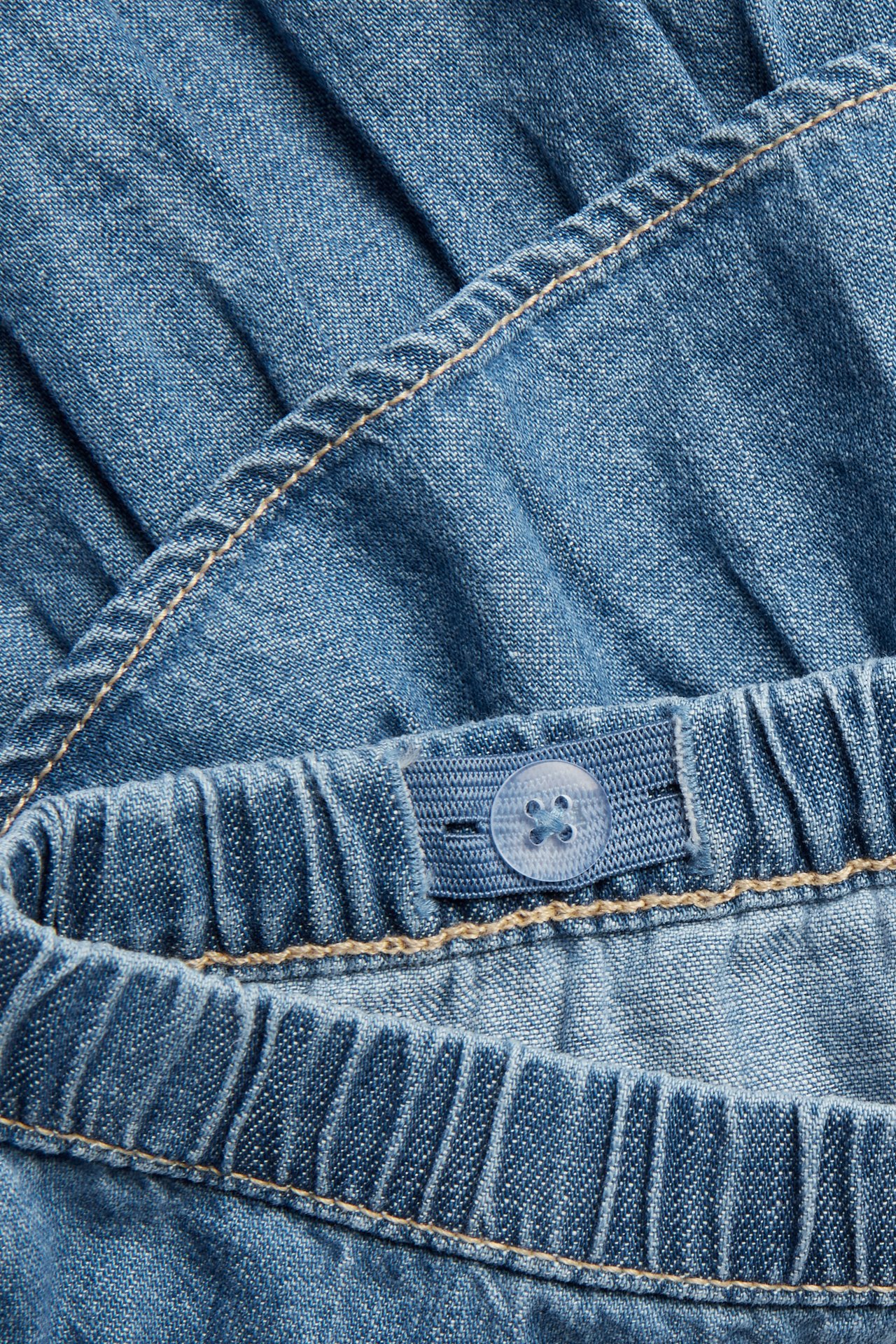 Lähikuva vaaleansinisestä denim-volangihameesta joustovyötäröllä ja säädettävällä napilla.