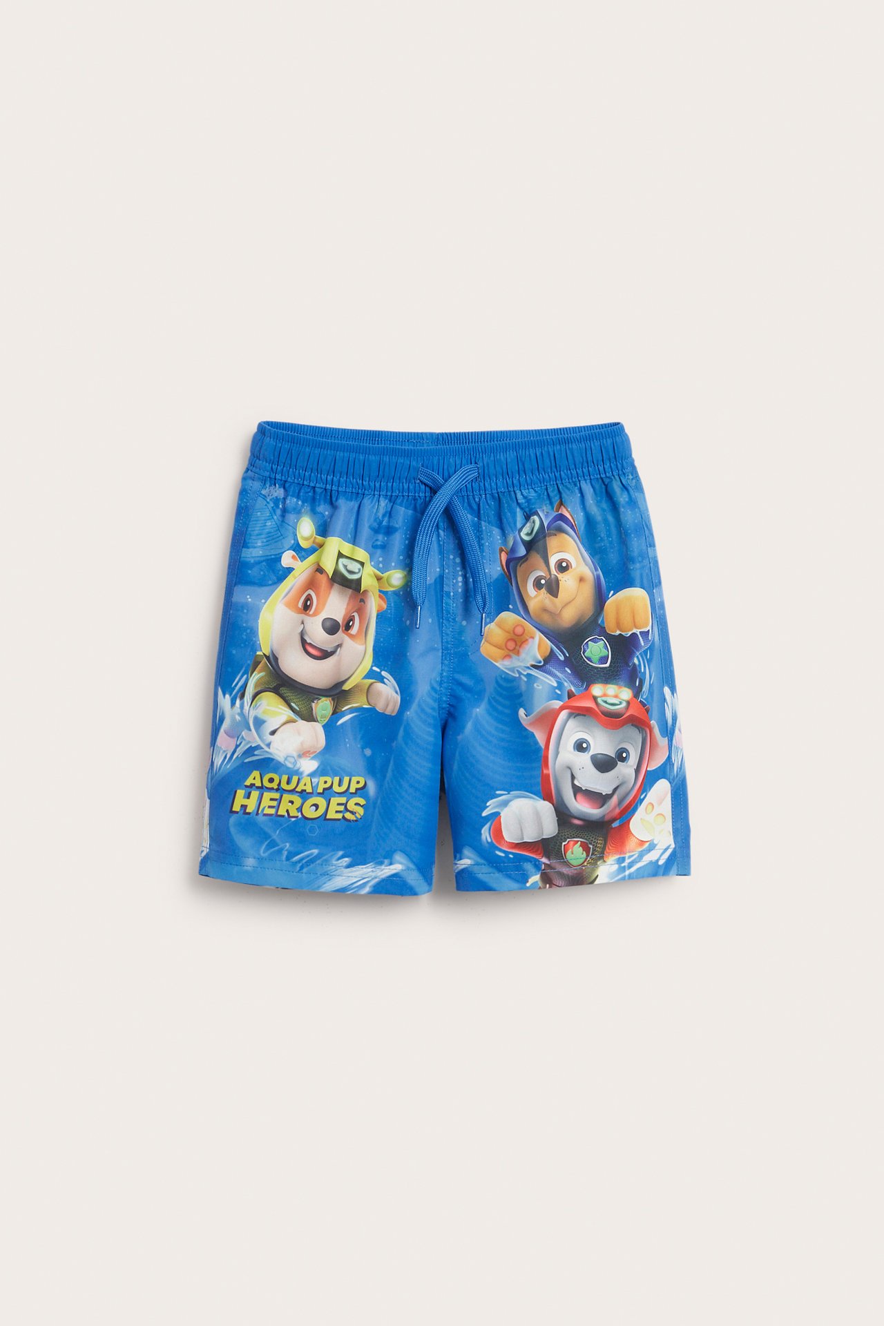 Forfra, blå badebukser til barn med elastisk snøring i midjen og Paw Patrol-trykk foran.