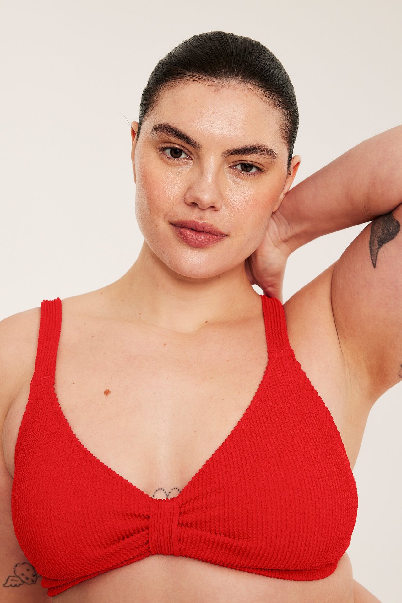 Edestä, nainen yllään punainen kuviollinen bikinin yläosa säädettävillä olkaimilla.