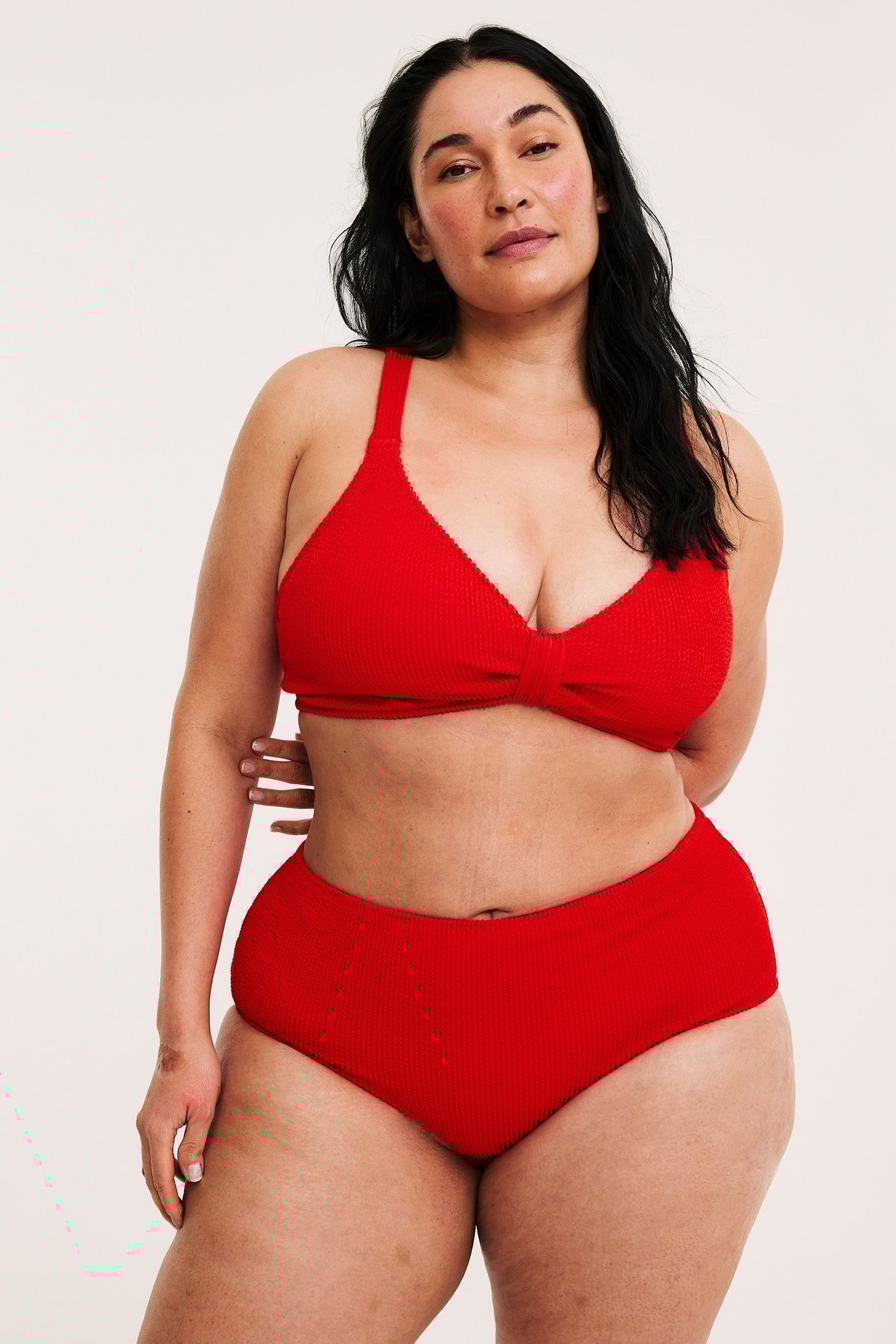 Edestä, nainen yllään punainen kuvioitu bikinitoppi ja yhteensopivat korkeavyötäröiset bikinialaosat.