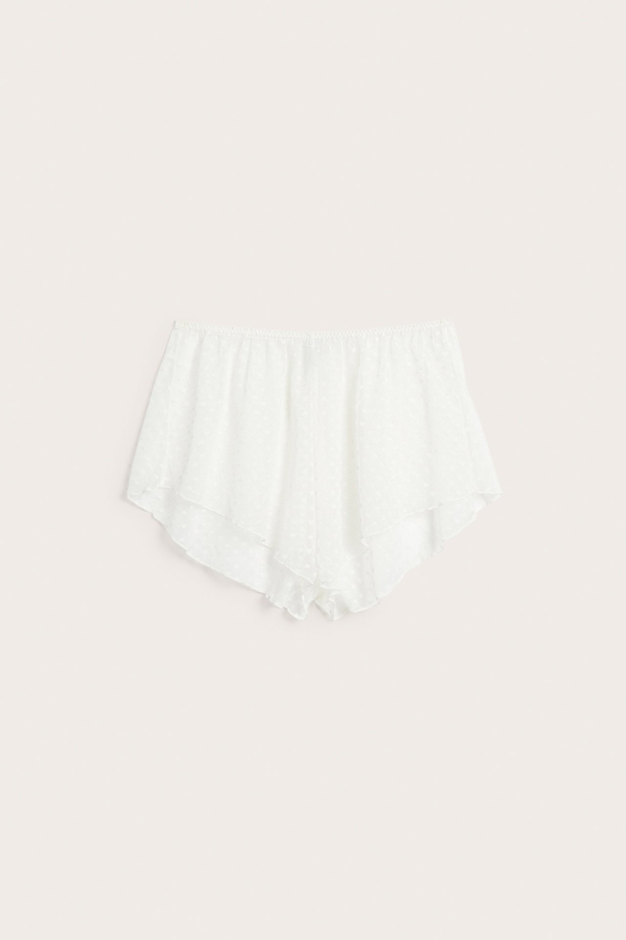 Fremvisning av offwhite shorts i gjennomsiktig mesh med hjertemønster og elastisk midje.