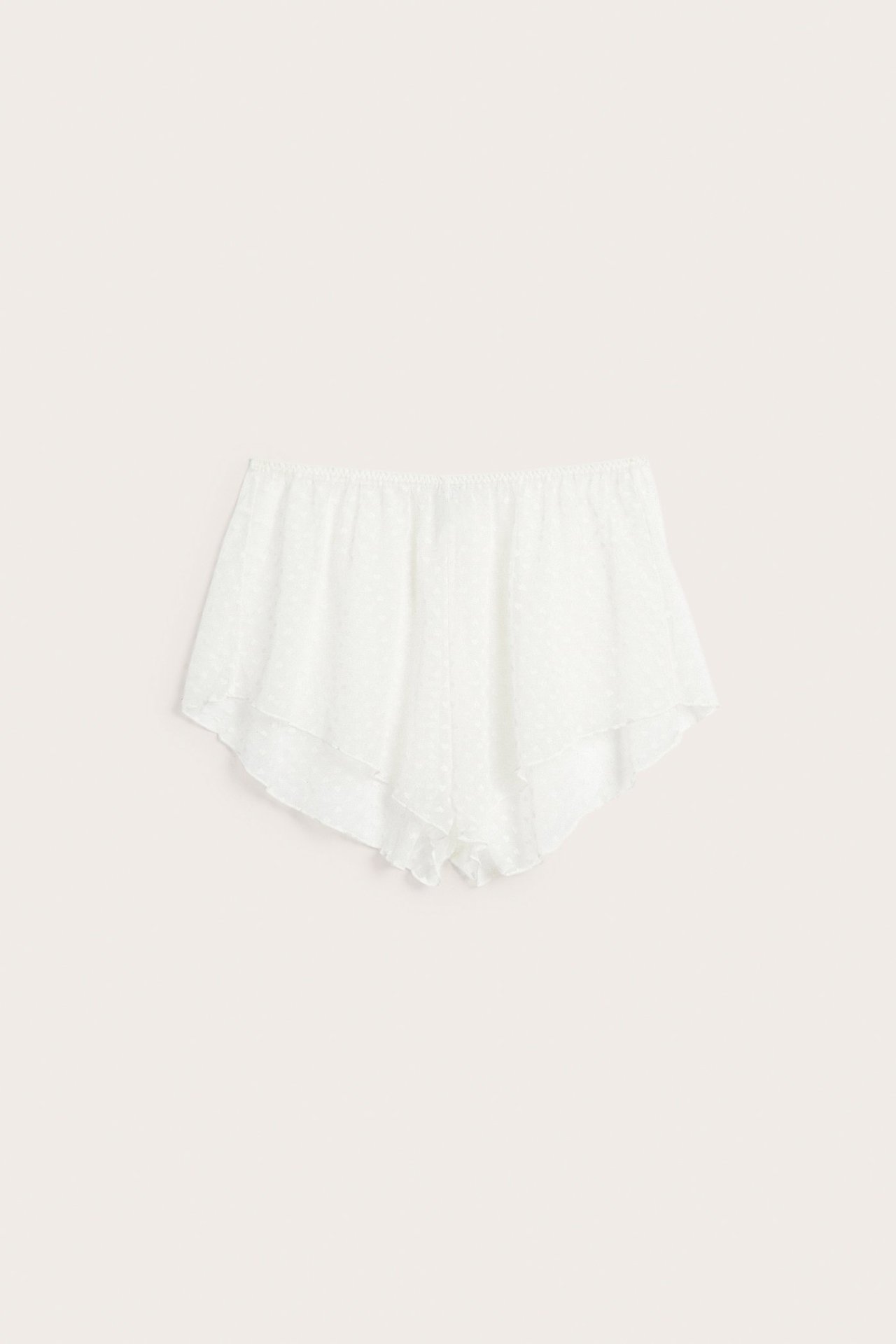 Fremvisning av offwhite shorts i gjennomsiktig mesh med hjertemønster og elastisk midje.