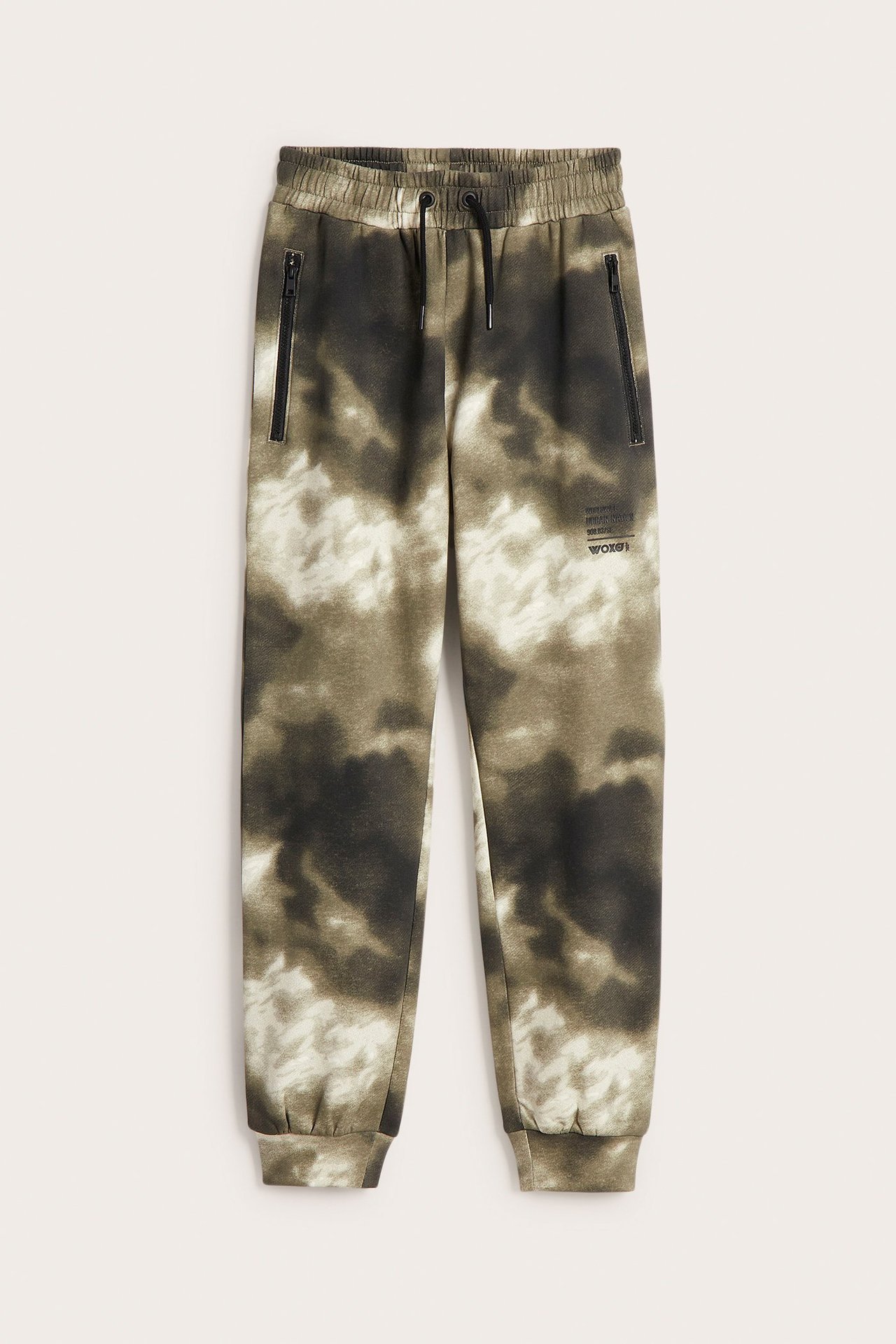 Widok z przodu: Dziecięce zielono-białe spodnie dresowe we wzór tie-dye z czarnymi kieszeniami na zamek i sznurkiem.