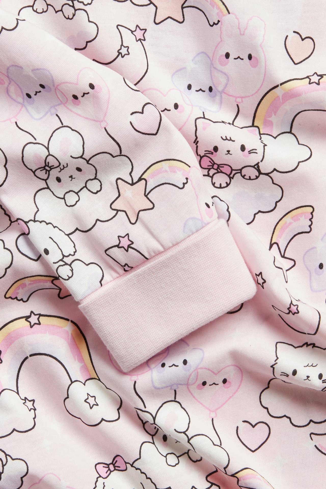 Zbliżenie: Dziecięca jasnoróżowa bawełniana koszula nocna z długim rękawem, zwierzęcym nadrukiem i wywijanymi mankietami.