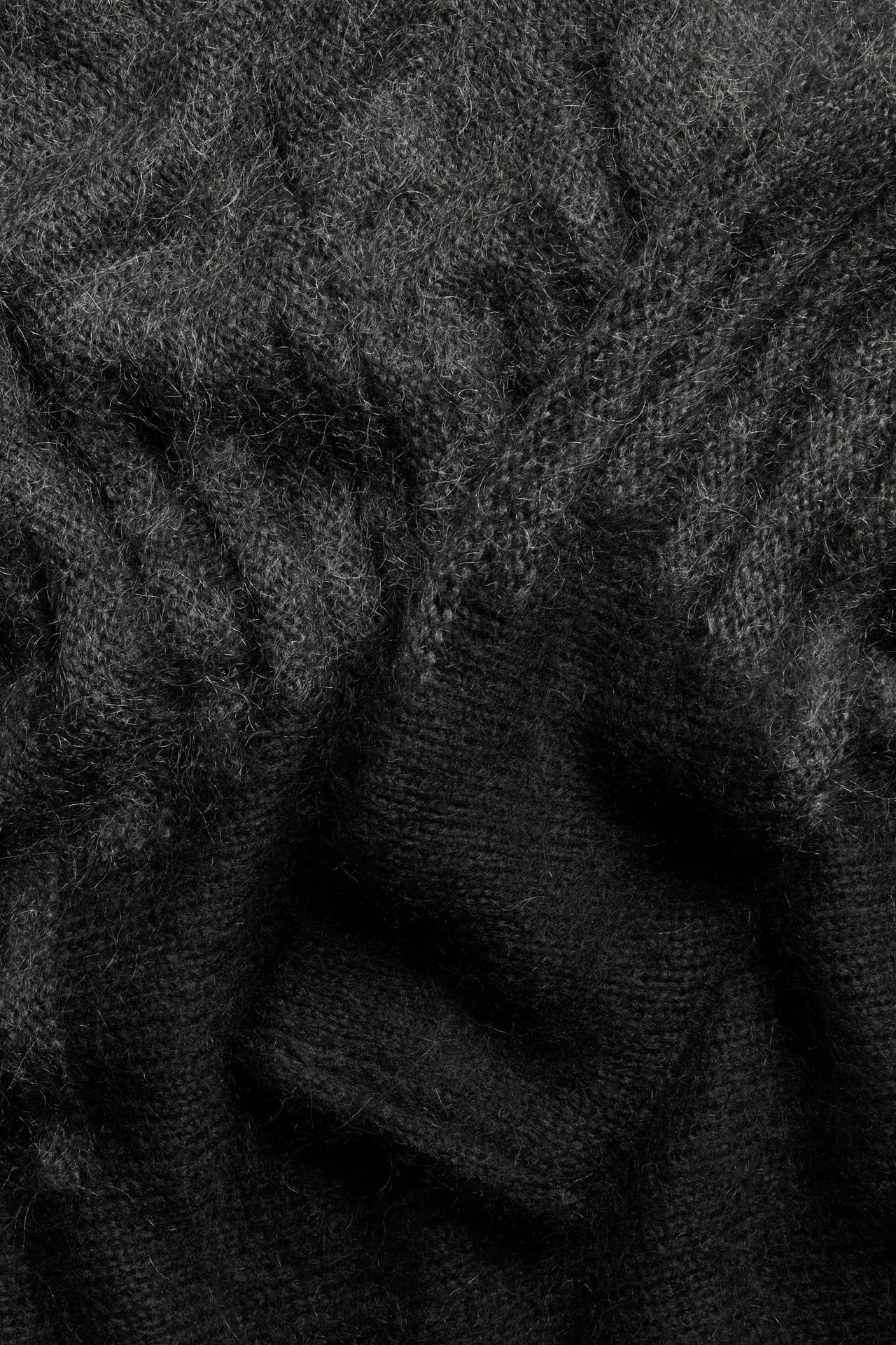 Zbliżenie czarnego swetra z dzianiny żakardowej z puszystej mieszanki moheru i wełny.