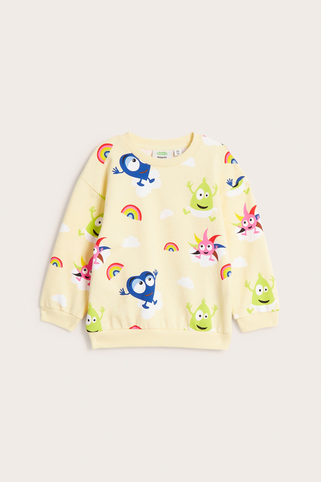Framifrån, ljusbeige babysweatshirt med färgglatt Babblarna-mönster, moln och regnbågar.