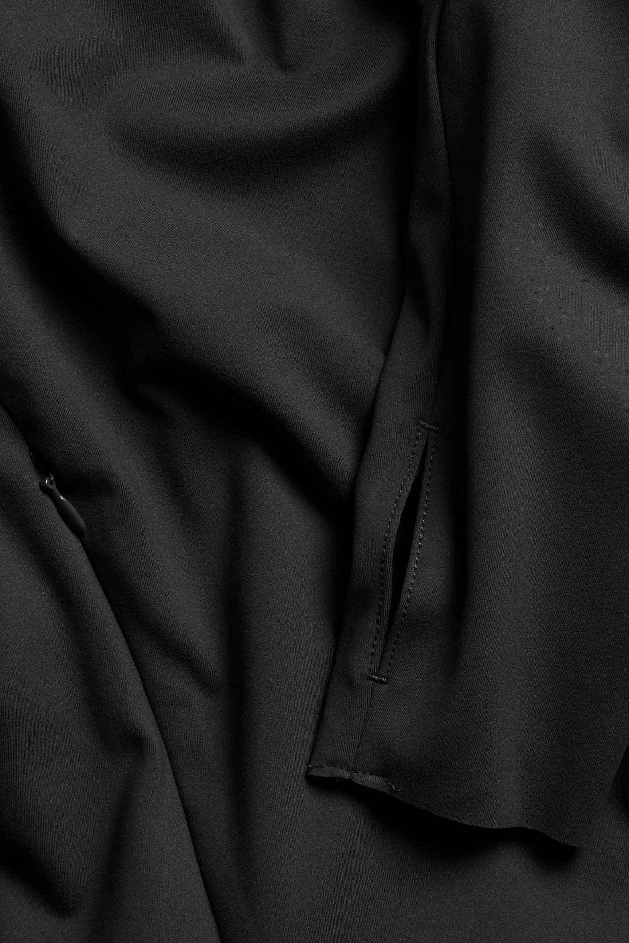 Lähikuva mustasta treenitakista, jossa on peukaloreikä hihassa ja vetoketjutasku.