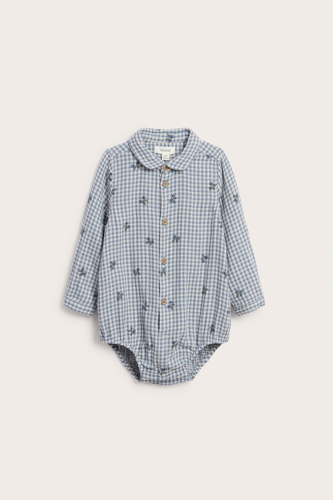 Frontutsikt av en baby blå- og hvitrutete bomulls skjortebody med blåbærtrykk, knapper foran.