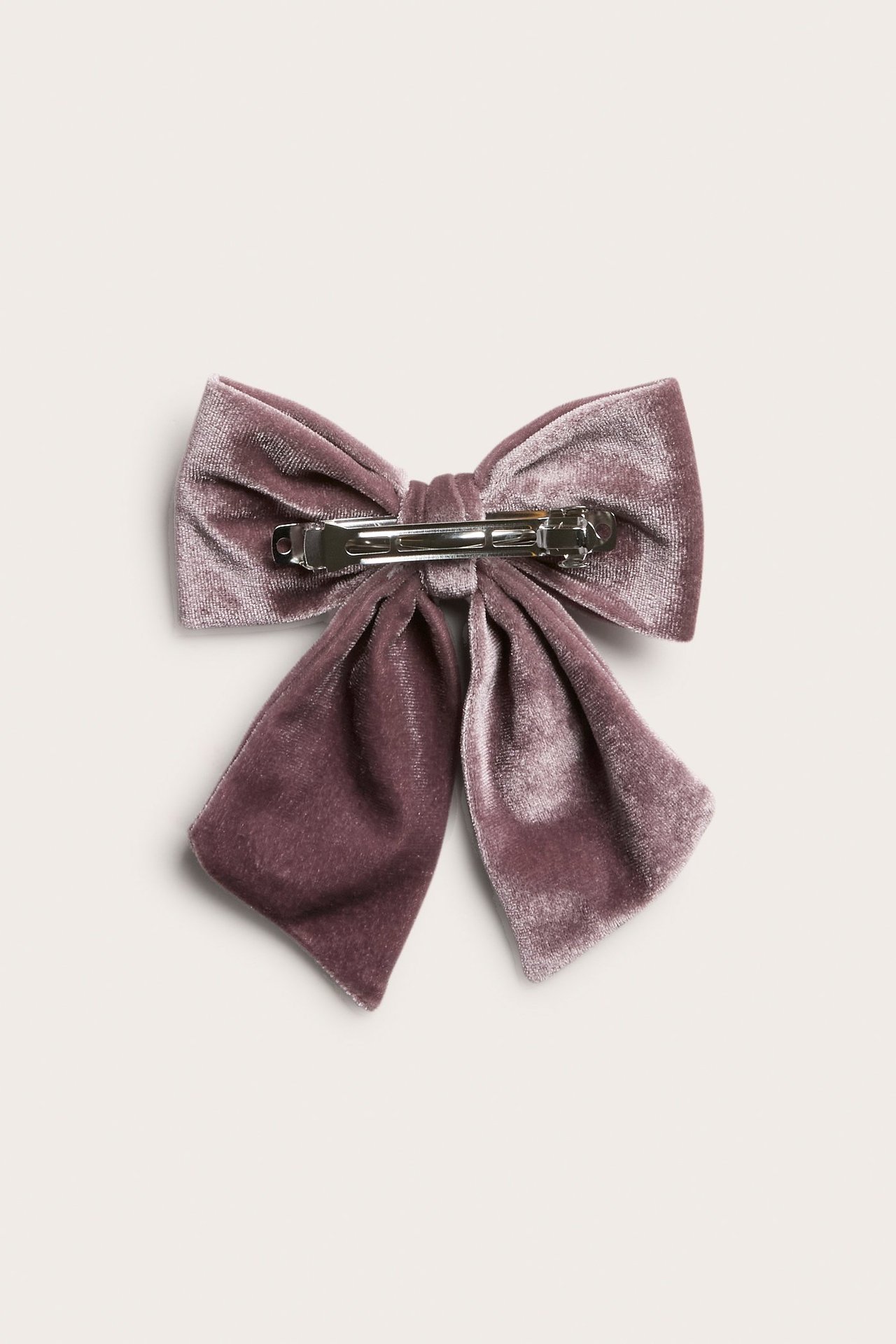 Ovenfra-bilde av en mørk lilla fløyelsrosett med en sølvfarget metallklemme.