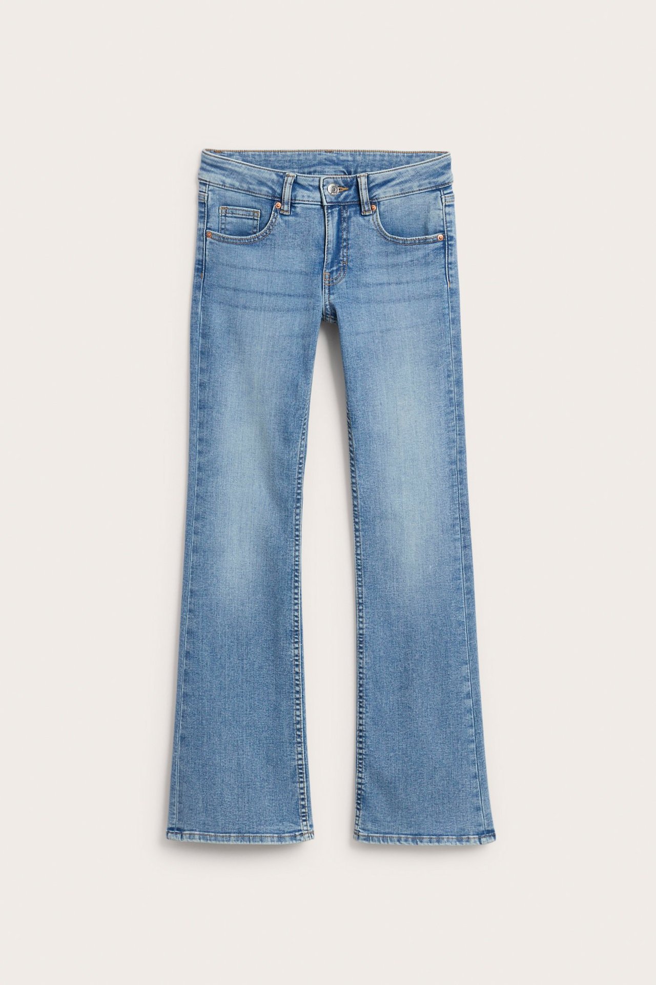 Frontvy av ljusblå stretchiga bootcut jeans med låg midja för barn, med synliga fickor.