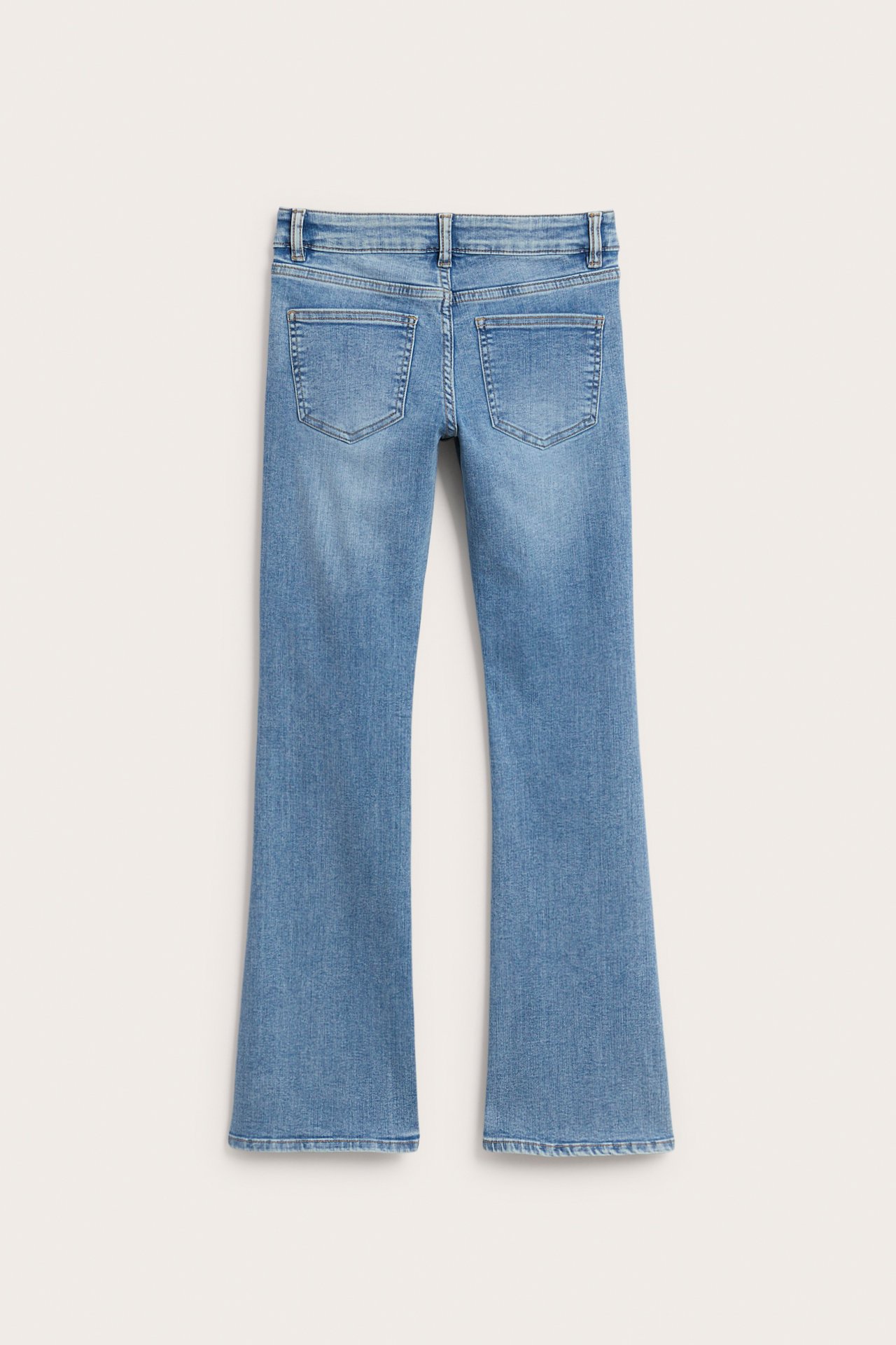 Widok z tyłu jasnoniebieskich jeansów bootcut z denimu, z niskim stanem, kieszeniami i szlufkami.