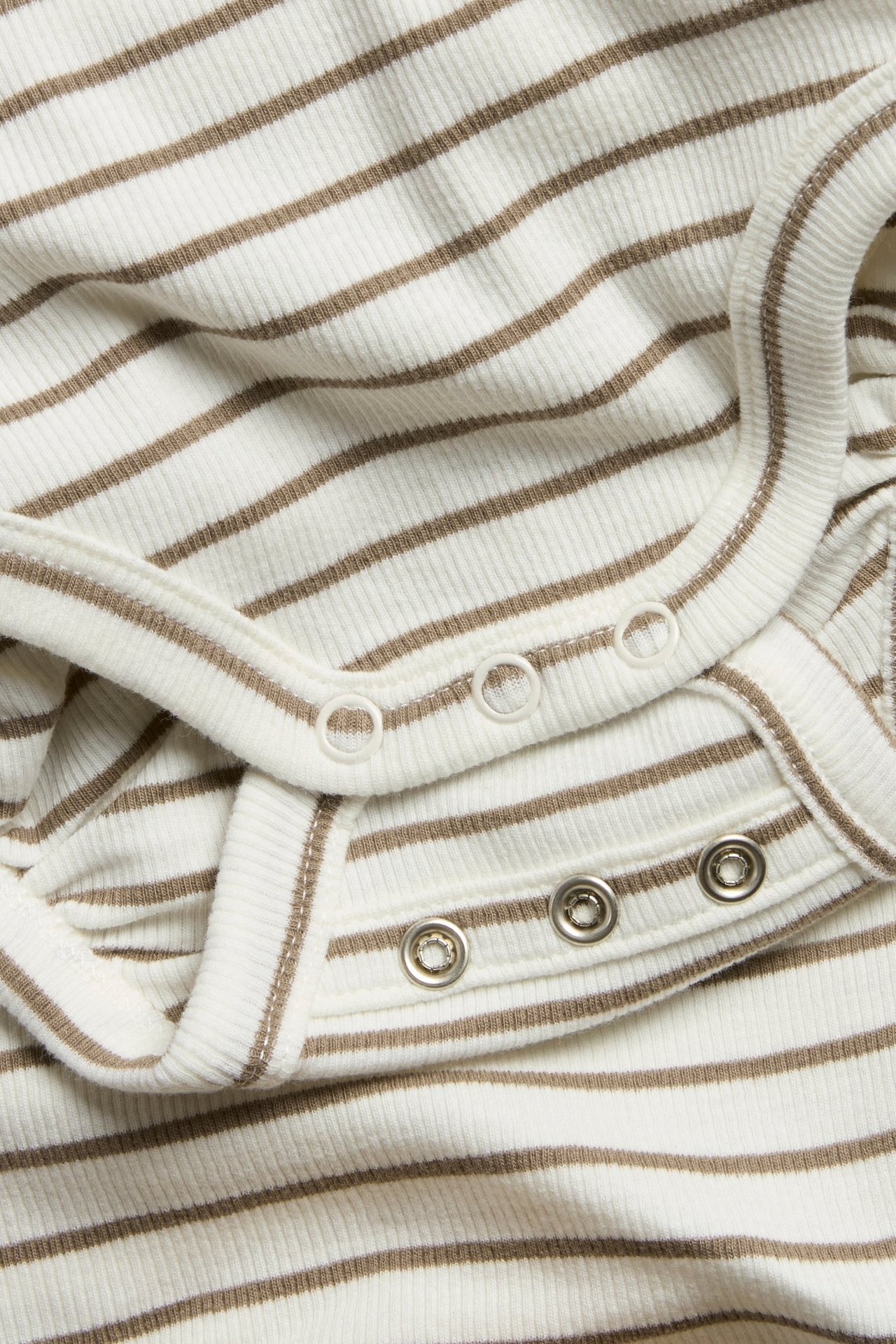 Zbliżenie na prążkowane, beżowo-brązowe body niemowlęce w paski z zatrzaskami.