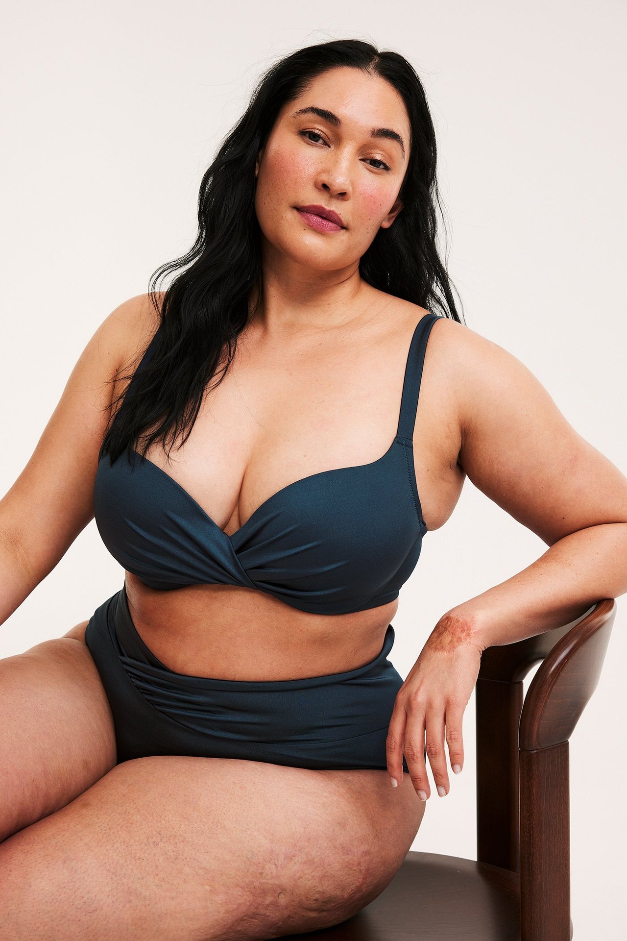 Edestäpäin: nainen tummansinisissä bikinirintaliiveissä kietaisuyksityiskohdalla ja yhteensopivissa korkeavyötäröisissä bikinin alaosissa.