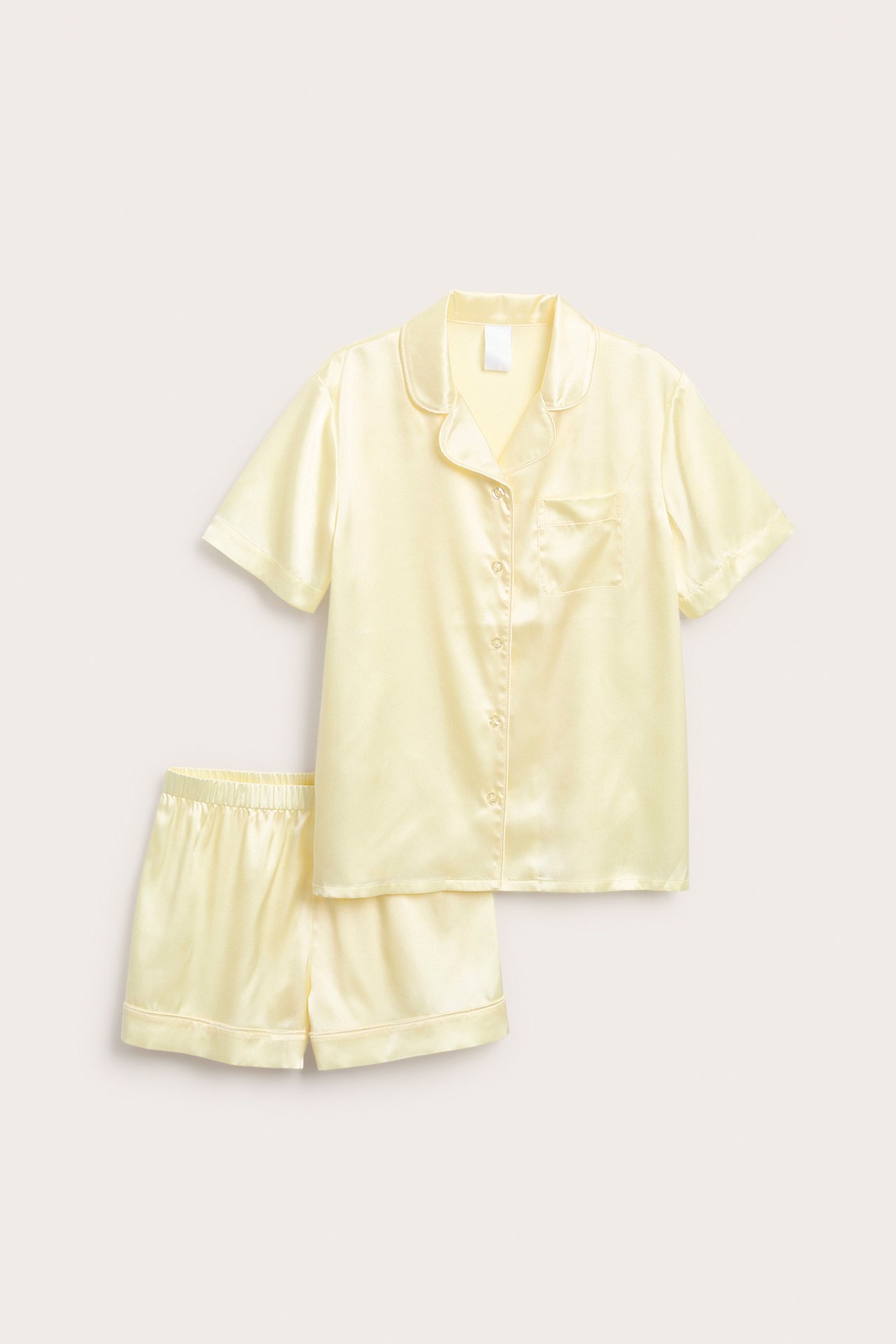 Forfra: Lysegul kortermet satengpyjamas med knappelukket skjorte, krage og matchende shorts.