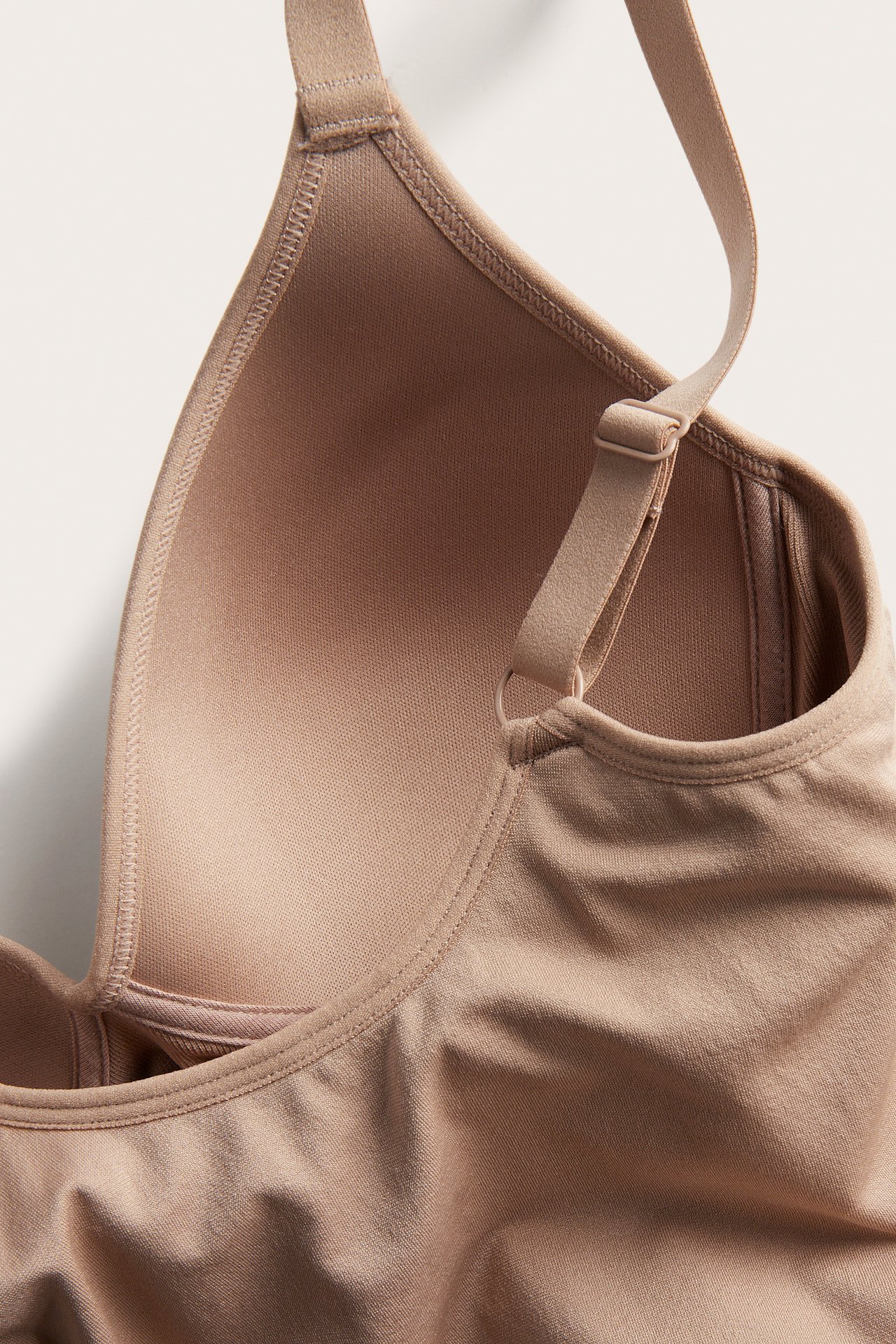 Lähikuva ruskeasta saumattomasta topista sisäänrakennetulla liivillä, muotoonpuristettu kuppi ja säädettävä olkain.