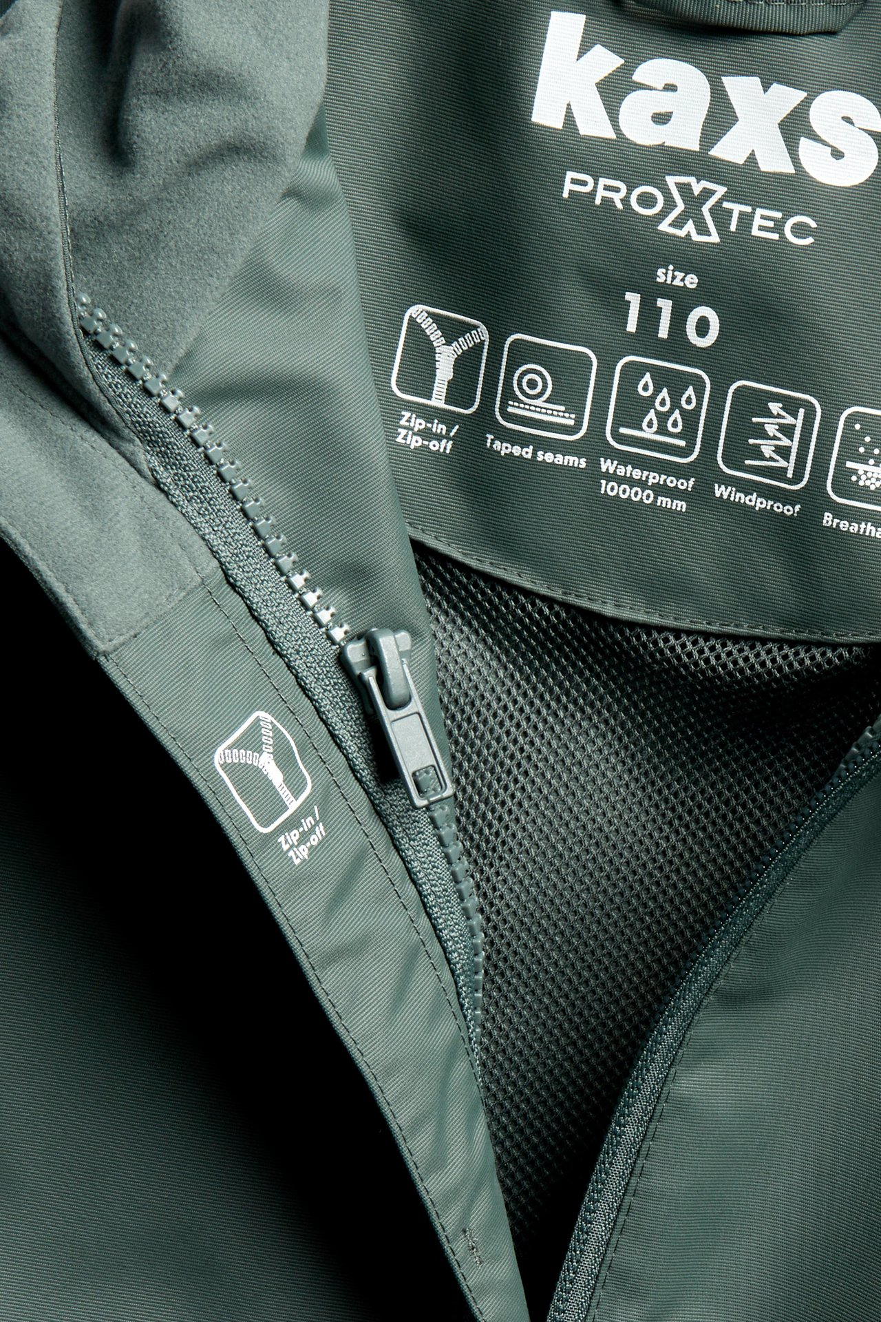 Närbild av en khakigrön vattentät skaljacka som visar zip-in/zip-off-funktion och inre nätfoder.