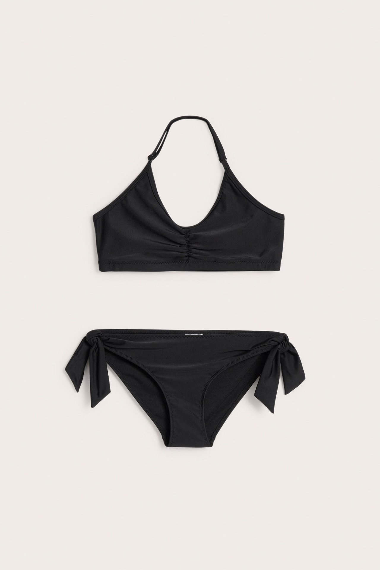 Widok z przodu czarnego dziecięcego bikini z marszczonym topem V i wiązanymi majtkami.
