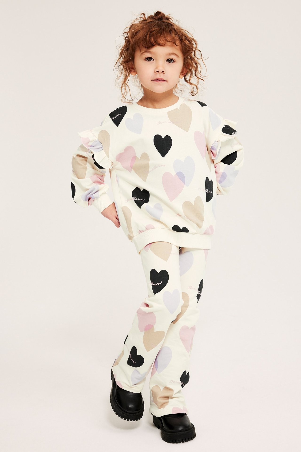 Framifrån: Kid i offwhite ribbade flare leggings och matchande topp med hjärtmönster.