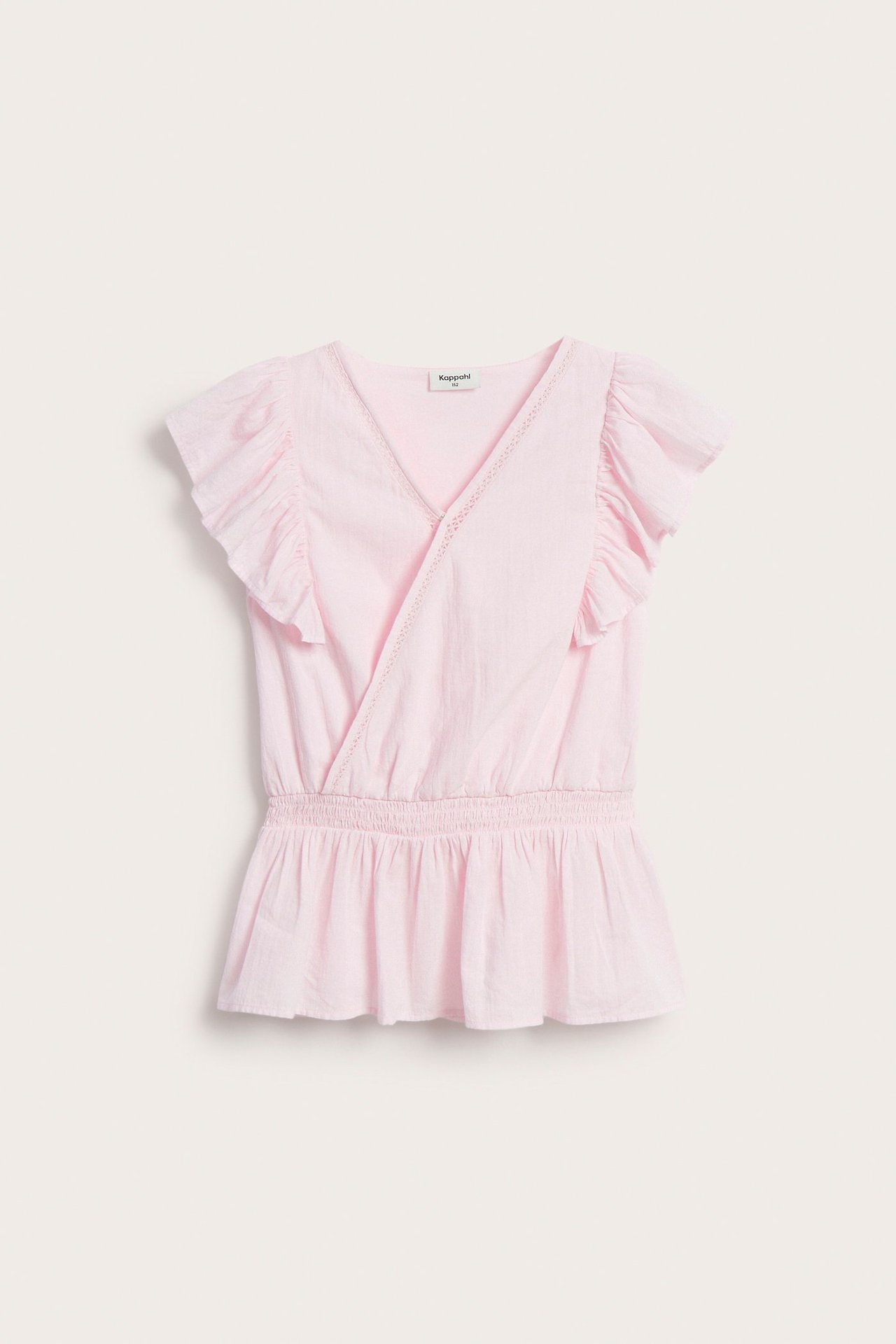 Framifrån: Ljusrosa omlottblus i bomull för barn med volanger, spetsdetaljer och smock i midjan.