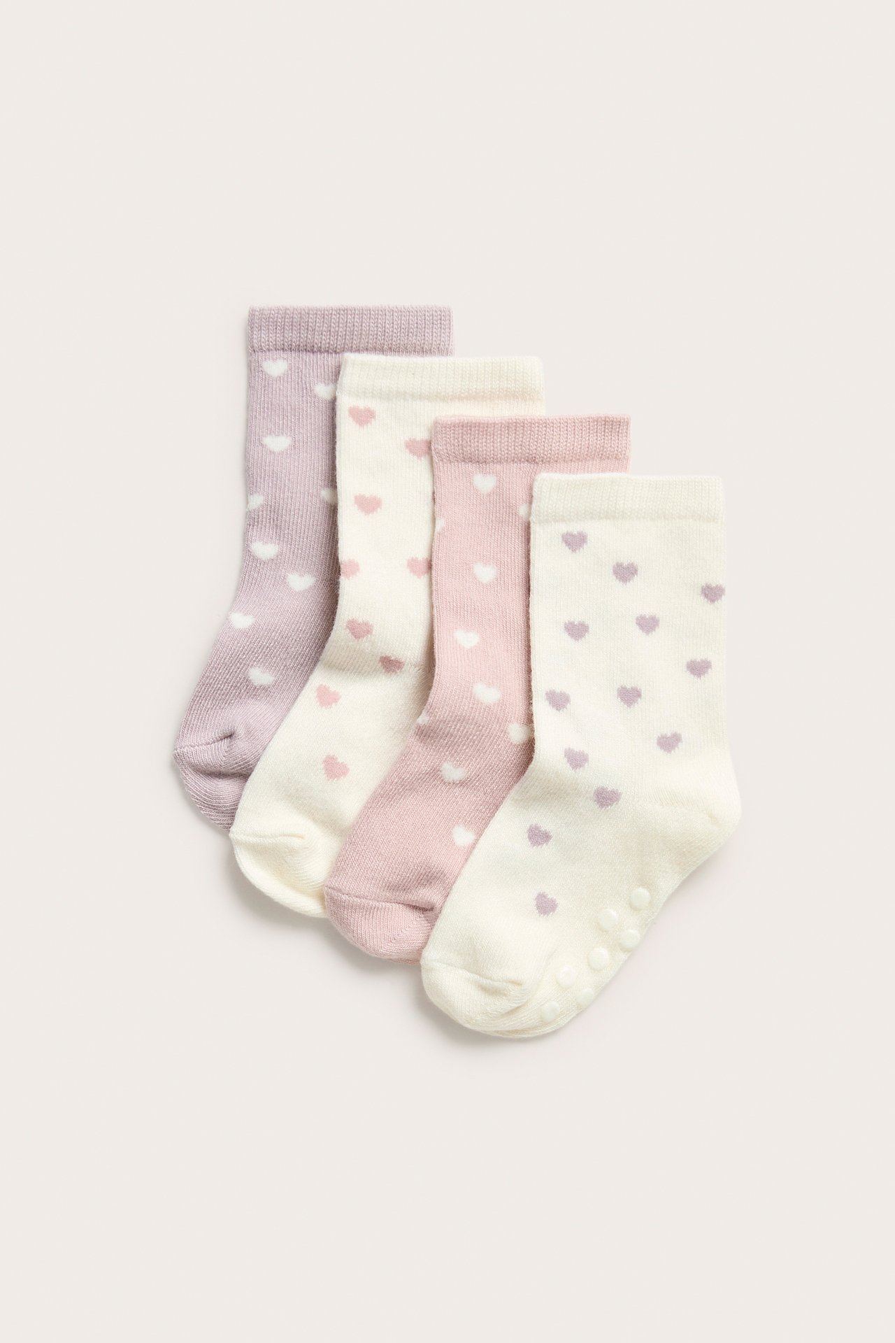 Sett forfra: fire babysokker i rosa, lilla og kremfarget med hjertemønster. Kremfargede sokker har antiskli.