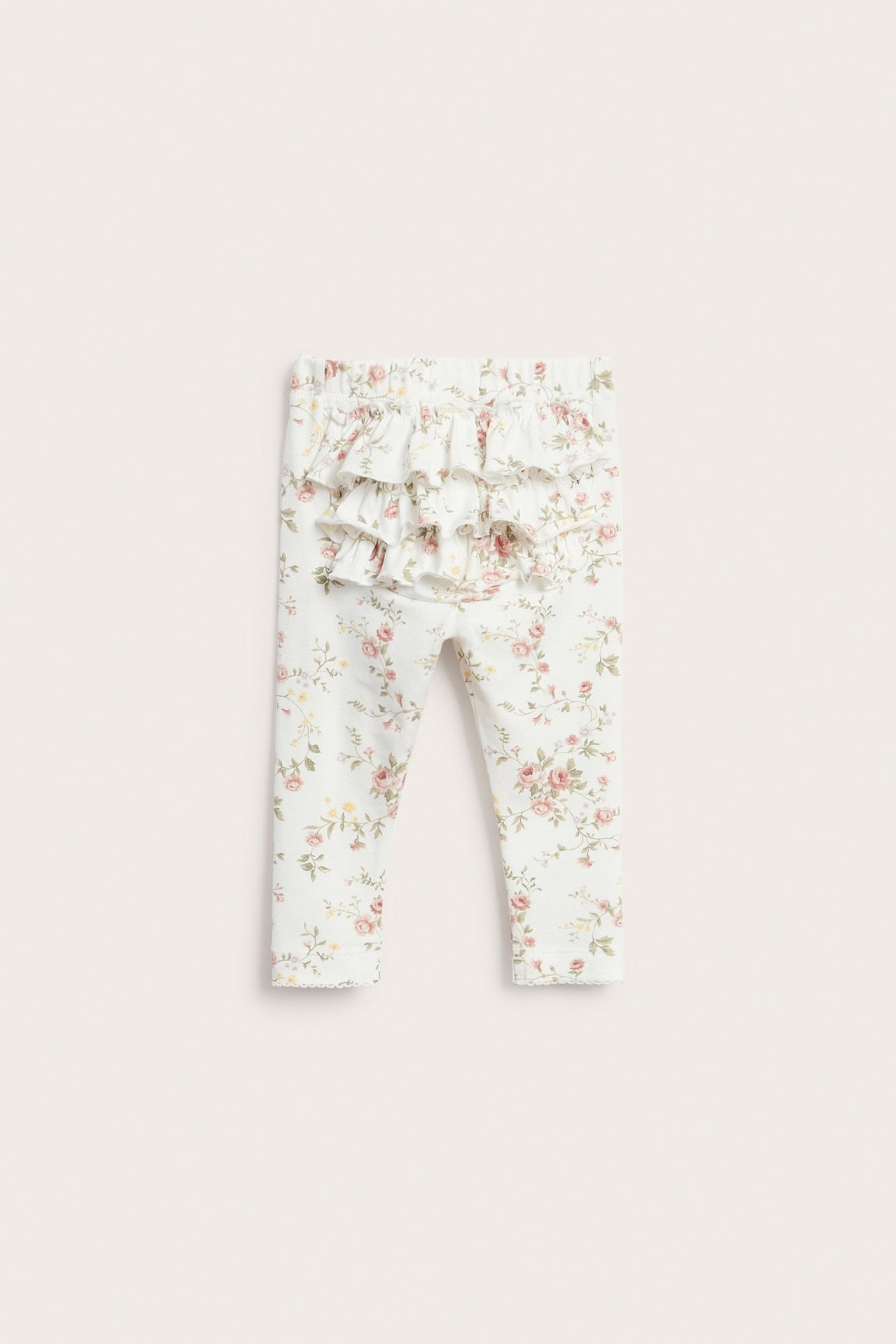 Forfra: babyens off-white blomstrete leggings med tre volanger bak og elastisk midje.