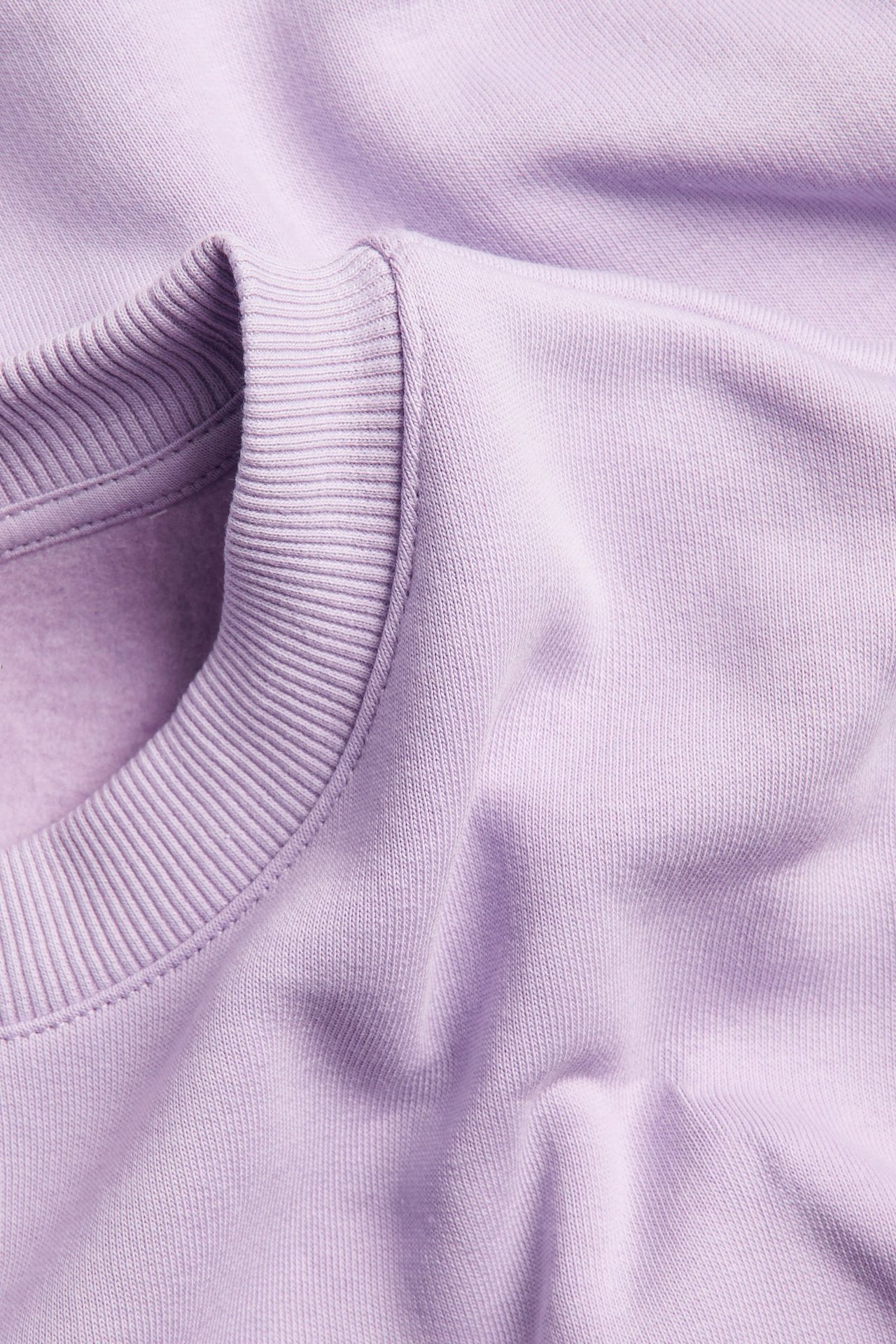 Lähikuva vaaleanlilasta collegepaidasta, jossa on uurrettu pääntie, puuvilla-polyesterisekoitetta.