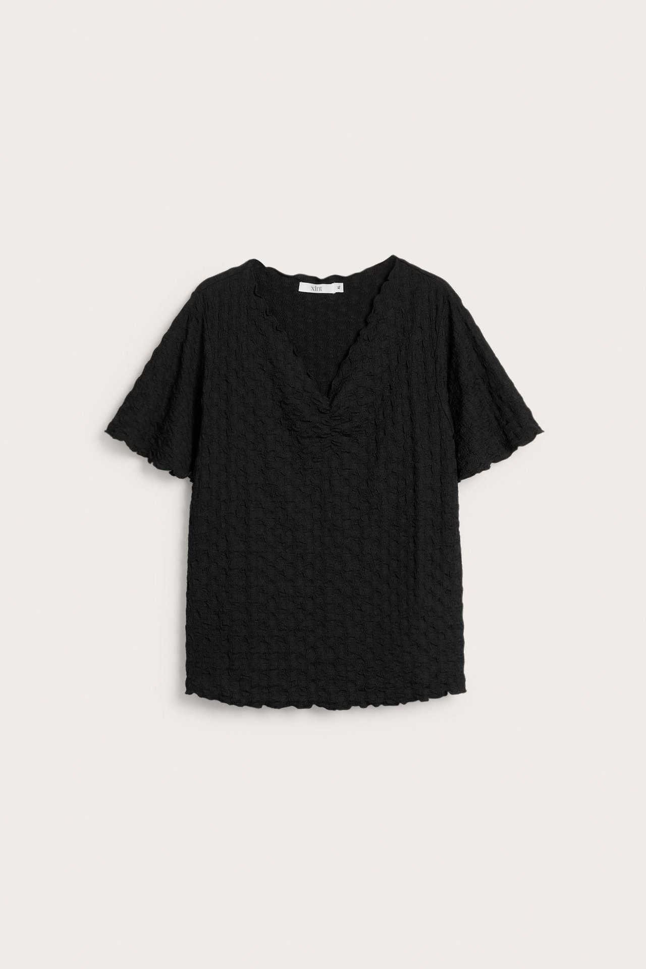 Widok z przodu czarnego, krótkiego, teksturowanego topu z marszczonym dekoltem w serek i falbankami.