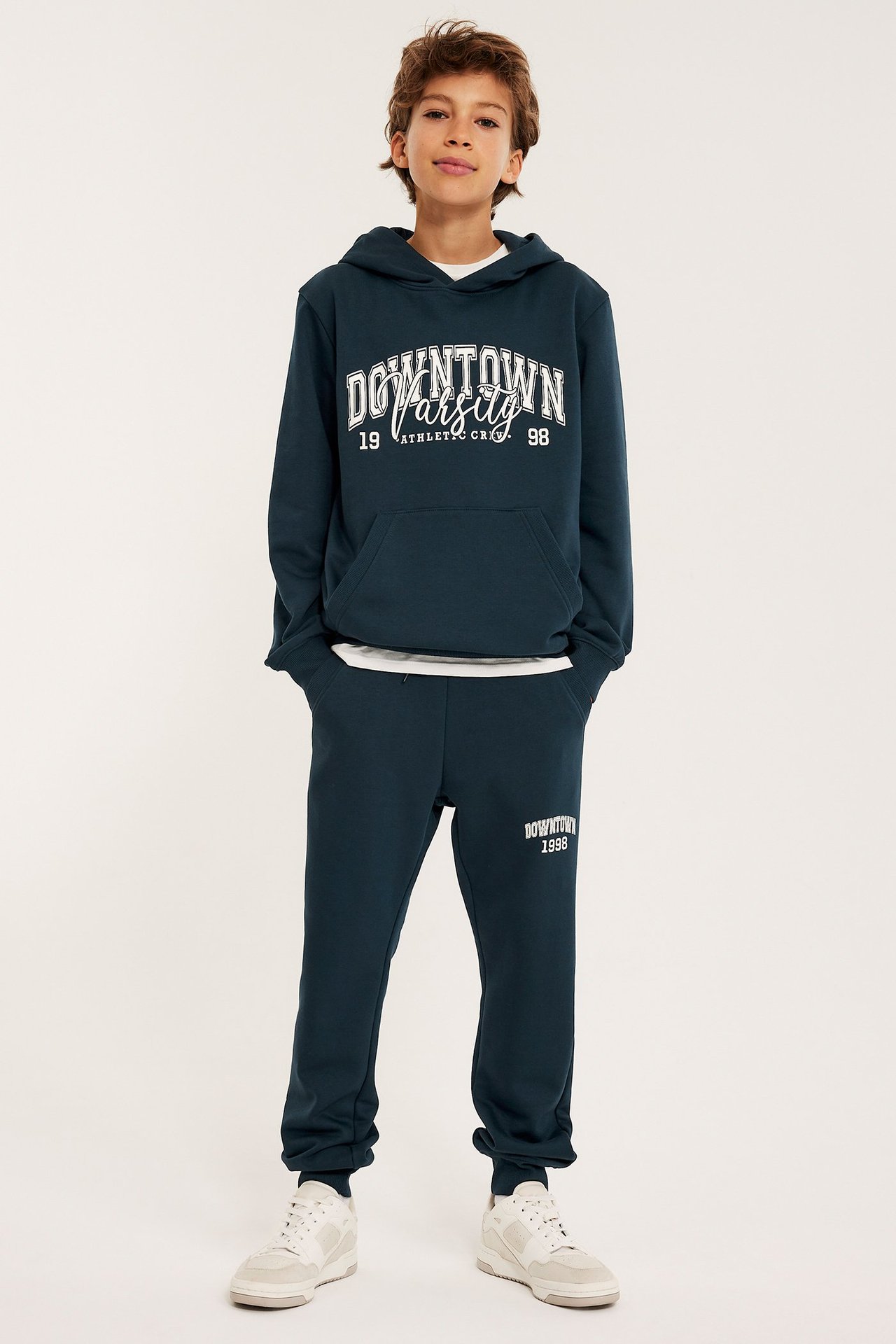 Edestäpäin: lapsi sinisessä painatetussa hupparissa ja yhteensopivissa sinisissä collegehousuissa resoreilla.