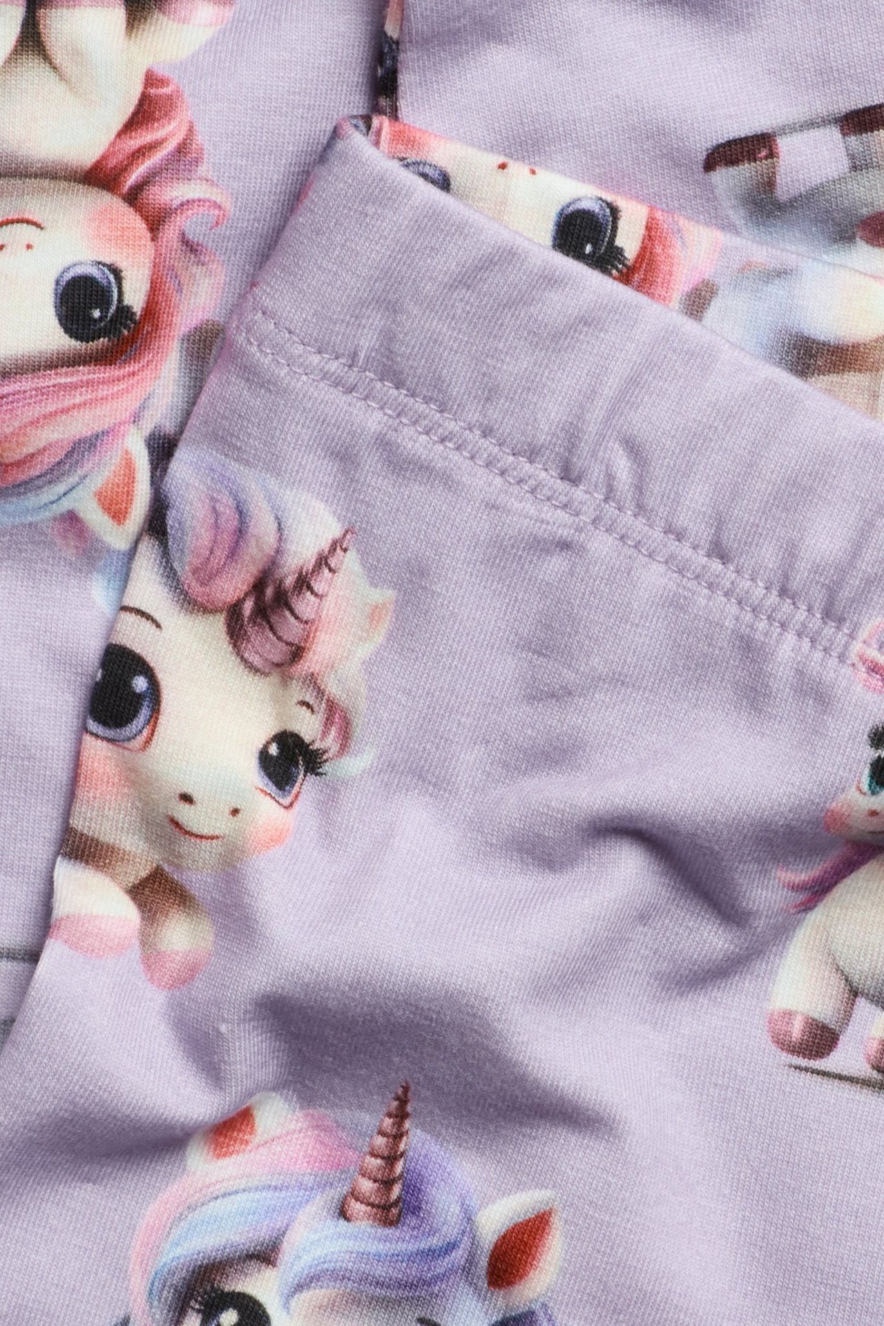 Lähikuva vaaleanliloista lasten leggingseistä, joissa on yksisarviskuvio.