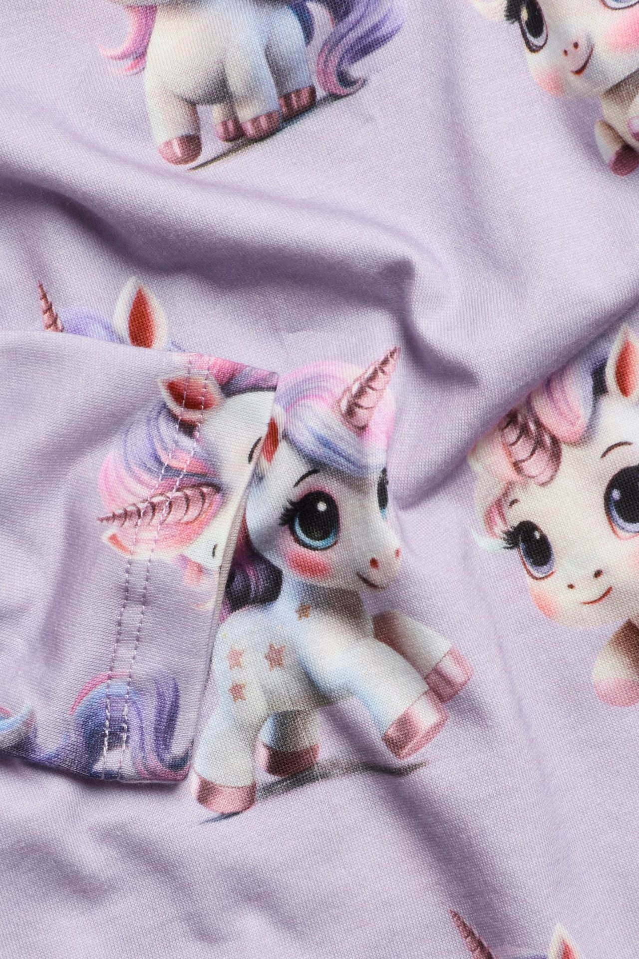 Lähikuva vaaleanliilasta puuvillaisesta pitkähihaisesta t-paidasta, jossa on yksisarviskuvio.