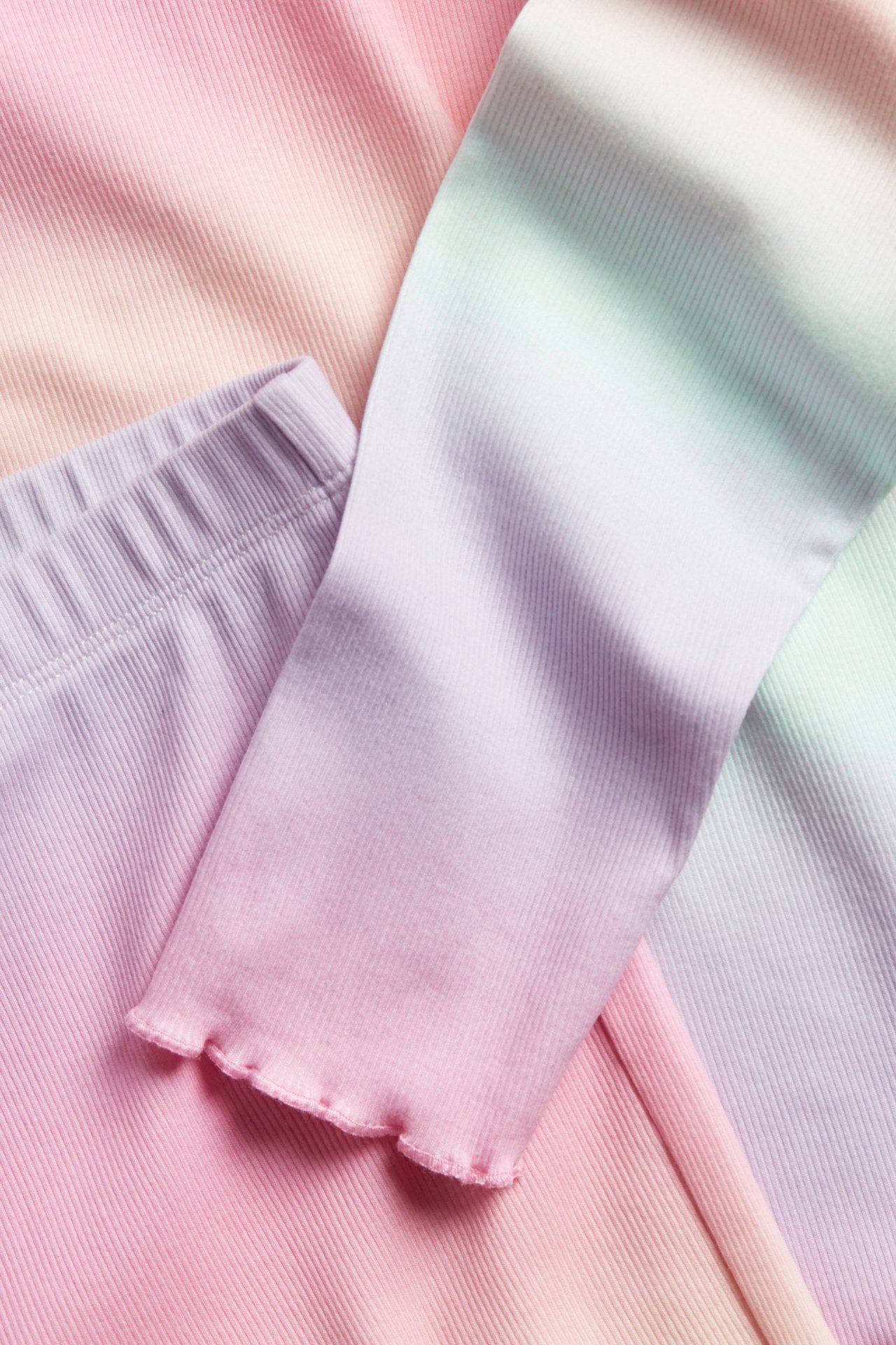 Zbliżenie prążkowanej piżamy w pastelowym odcieniu różu, fioletu, mięty i bieli.