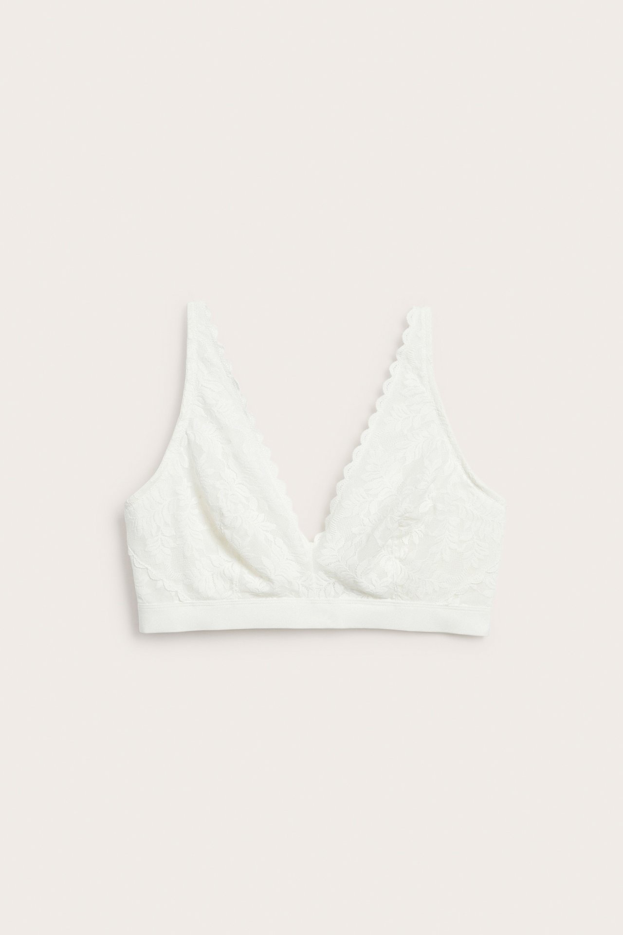 Framifrån, en offwhite spetsbralette med mjuk V-ringning och vågiga kanter.