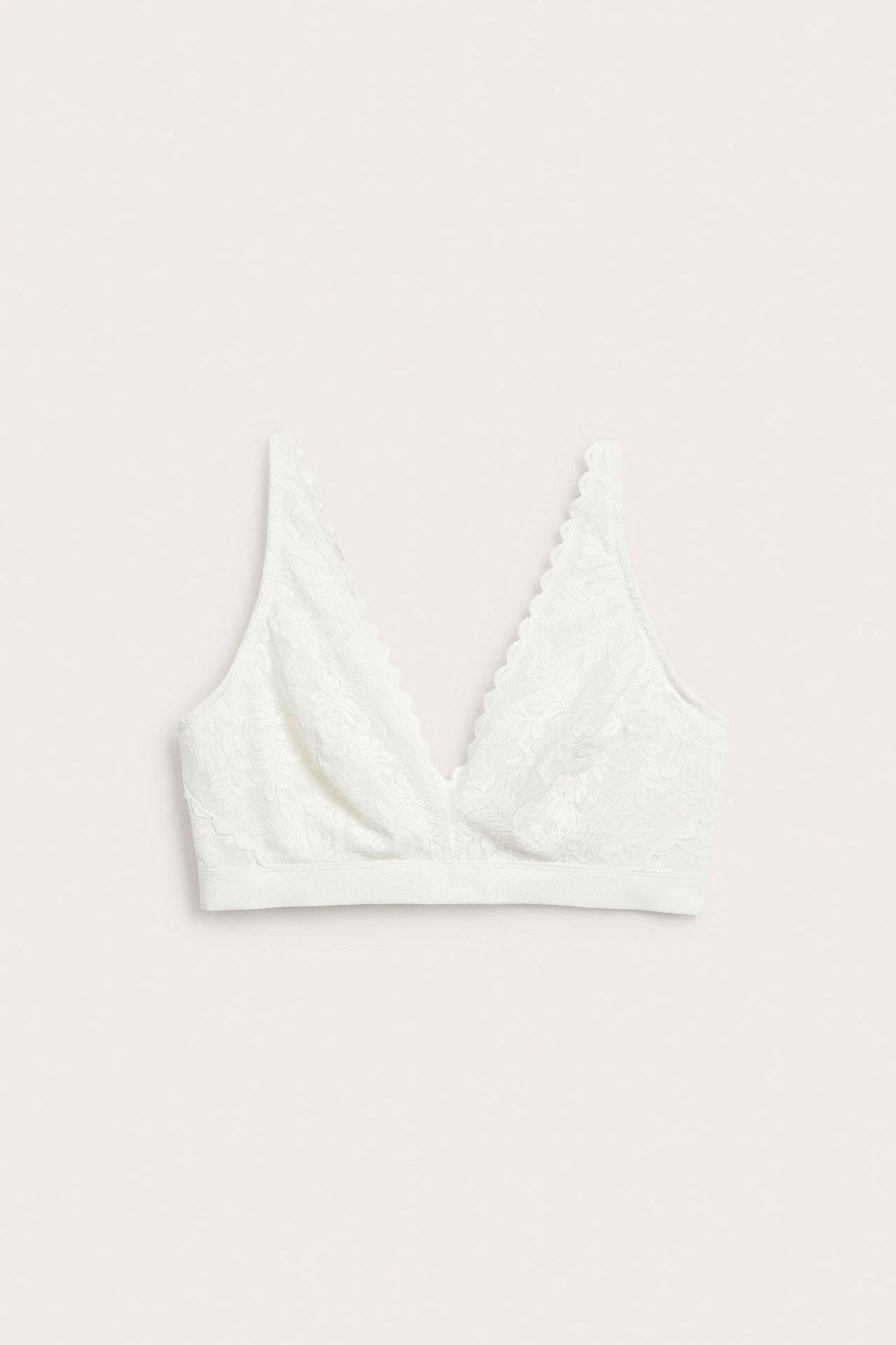 Framifrån, en offwhite spetsbralette med mjuk V-ringning och vågiga kanter.