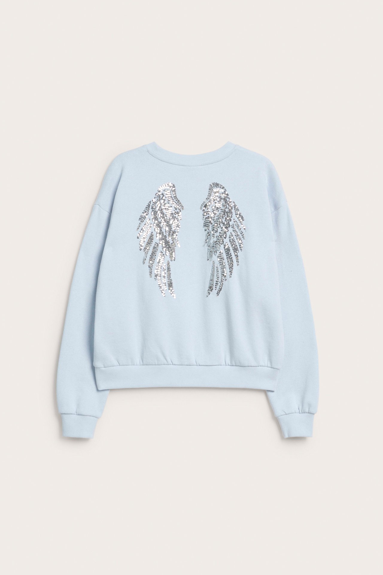 Bakifrån, en ljusblå sweatshirt för barn med silverfärgade paljettvingar på ryggen.