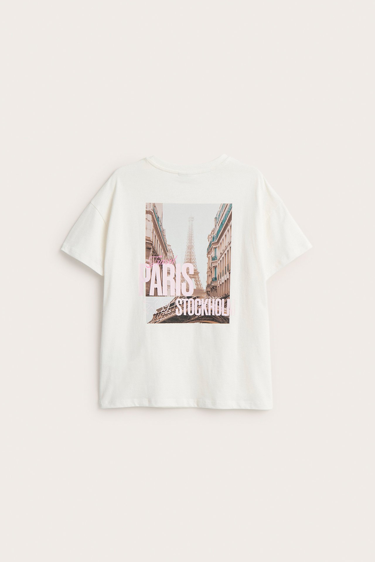 Bakfra: offwhite bomulls-t-skjorte med stort trykk av Eiffeltårnet og teksten 'PARIS STOCKHOLM'.